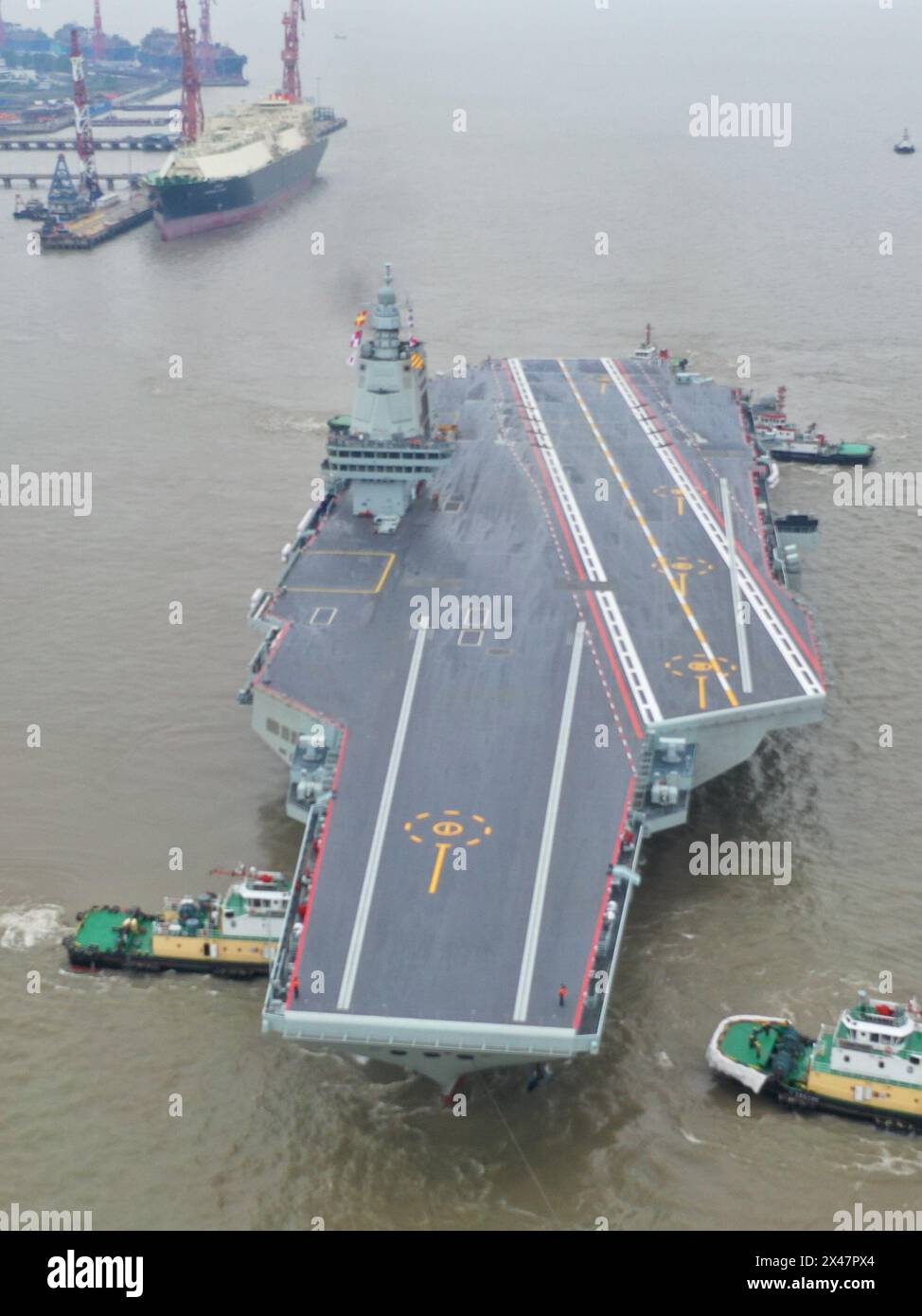 (240501) -- SHANGHAI, 1° maggio 2024 (Xinhua) -- una foto di un drone aereo scattata il 1° maggio 2024 mostra i rimorchiatori che trainano la terza portaerei cinese, la Fujian, lontano da un molo nella zona orientale di Shanghai. La terza portaerei cinese, la Fujian, è partita per le prime prove in mare mercoledì mattina. Le prove in mare testeranno principalmente l'affidabilità e la stabilità dei sistemi elettrici e di propulsione della portaerei. Dal suo lancio nel giugno 2022, il Fujian ha completato le prove di ormeggio, i lavori di allestimento e le regolazioni delle attrezzature. Ha soddisfatto i requisiti tecnici per le prove in mare. ( Foto Stock