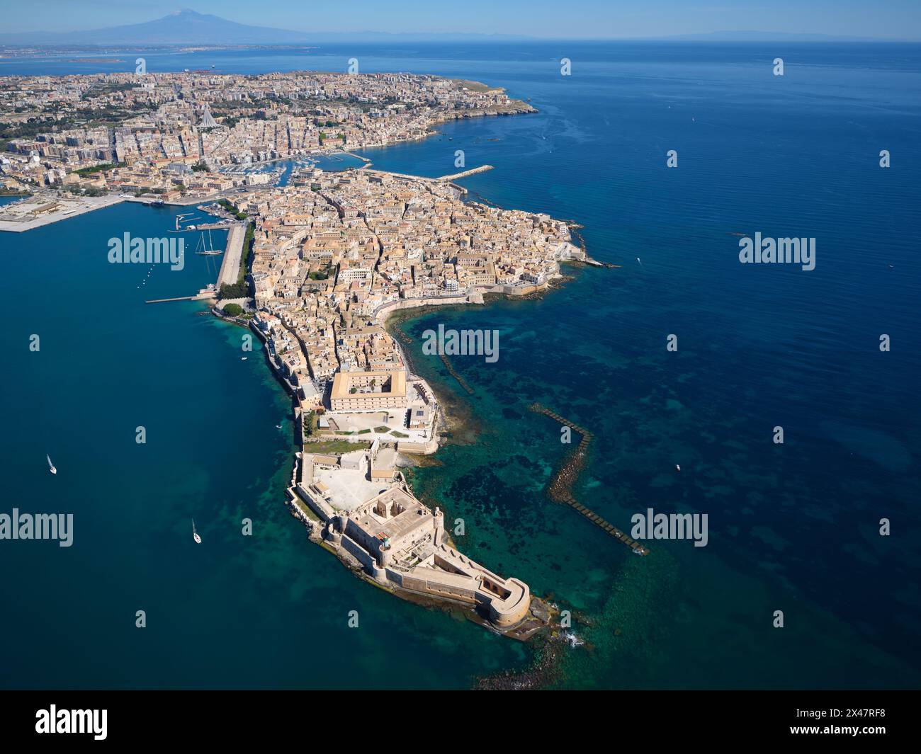 VISTA AEREA. L'isola di Ortigia e la città di Siracusa, l'Etna sono visibili in lontananza. Provincia di Siracusa, Sicilia, Italia. Foto Stock