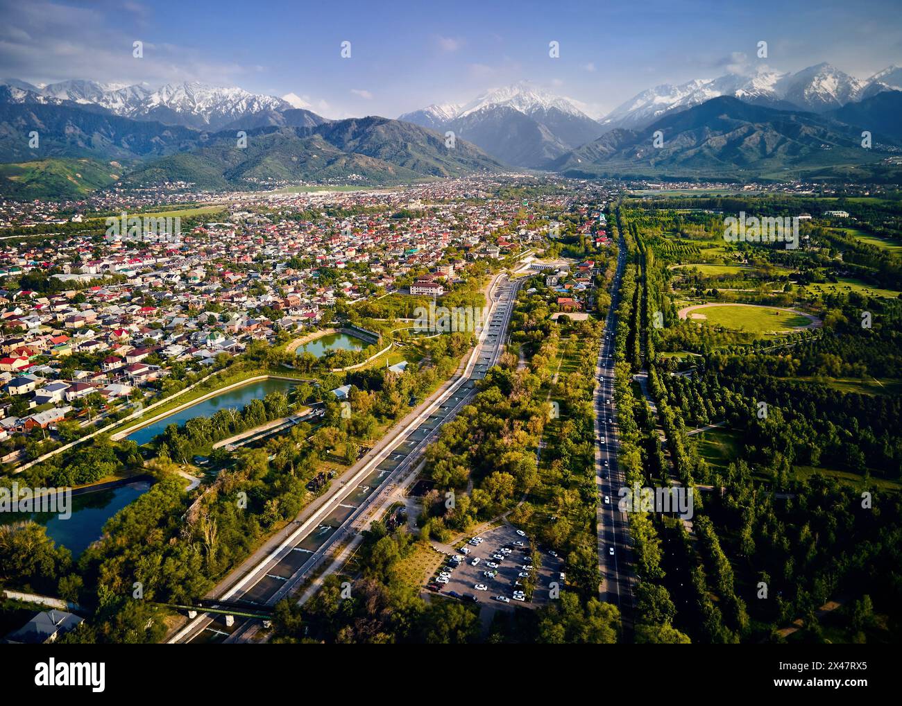 Vista aerea del drone panorama del grande fiume Almaty e le case con scenario di montagne di neve sullo sfondo nella città di Almaty, Kazakistan Foto Stock