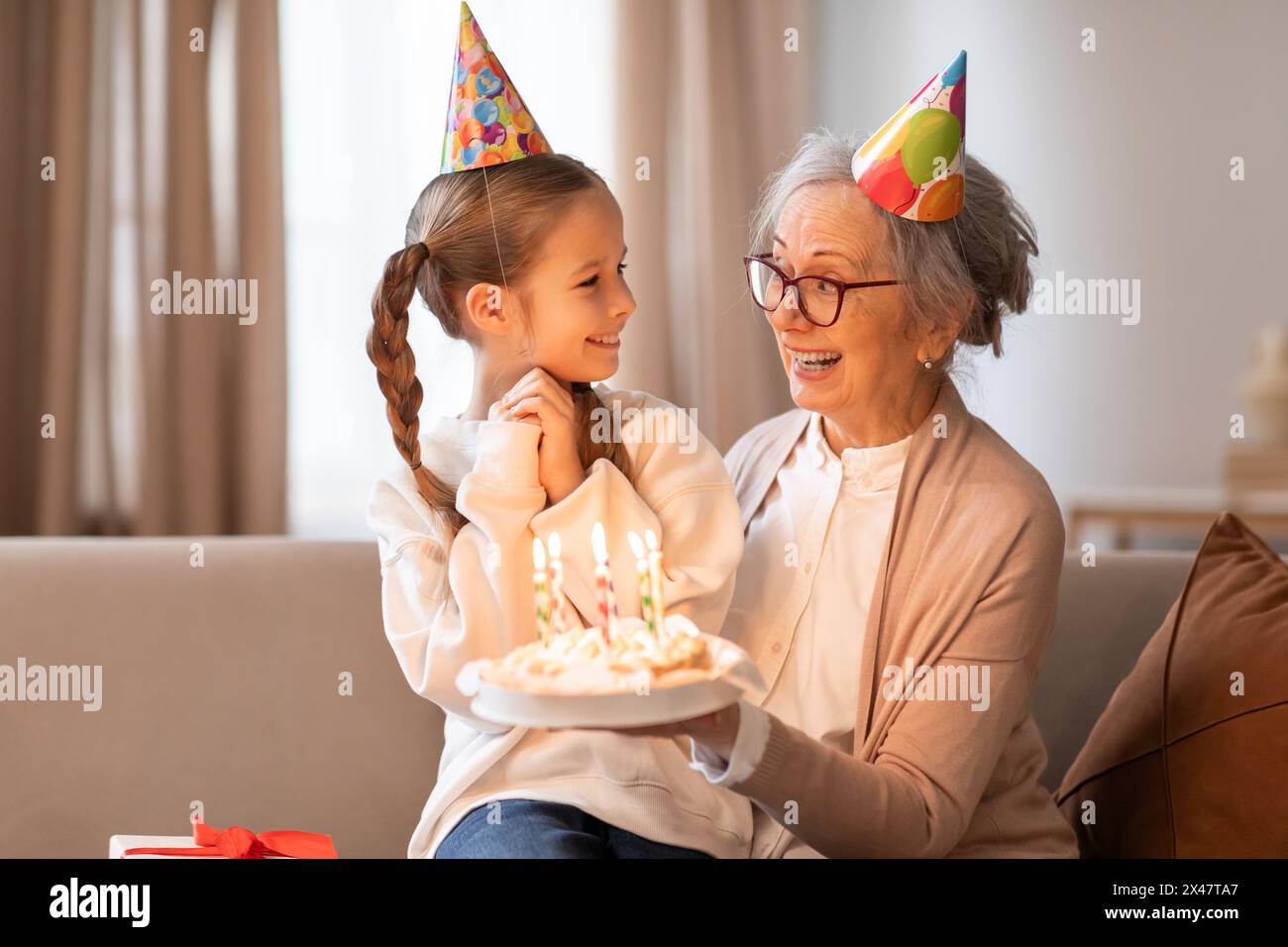 Gioiosa nonna che celebra il compleanno delle ragazze con una torta Foto Stock