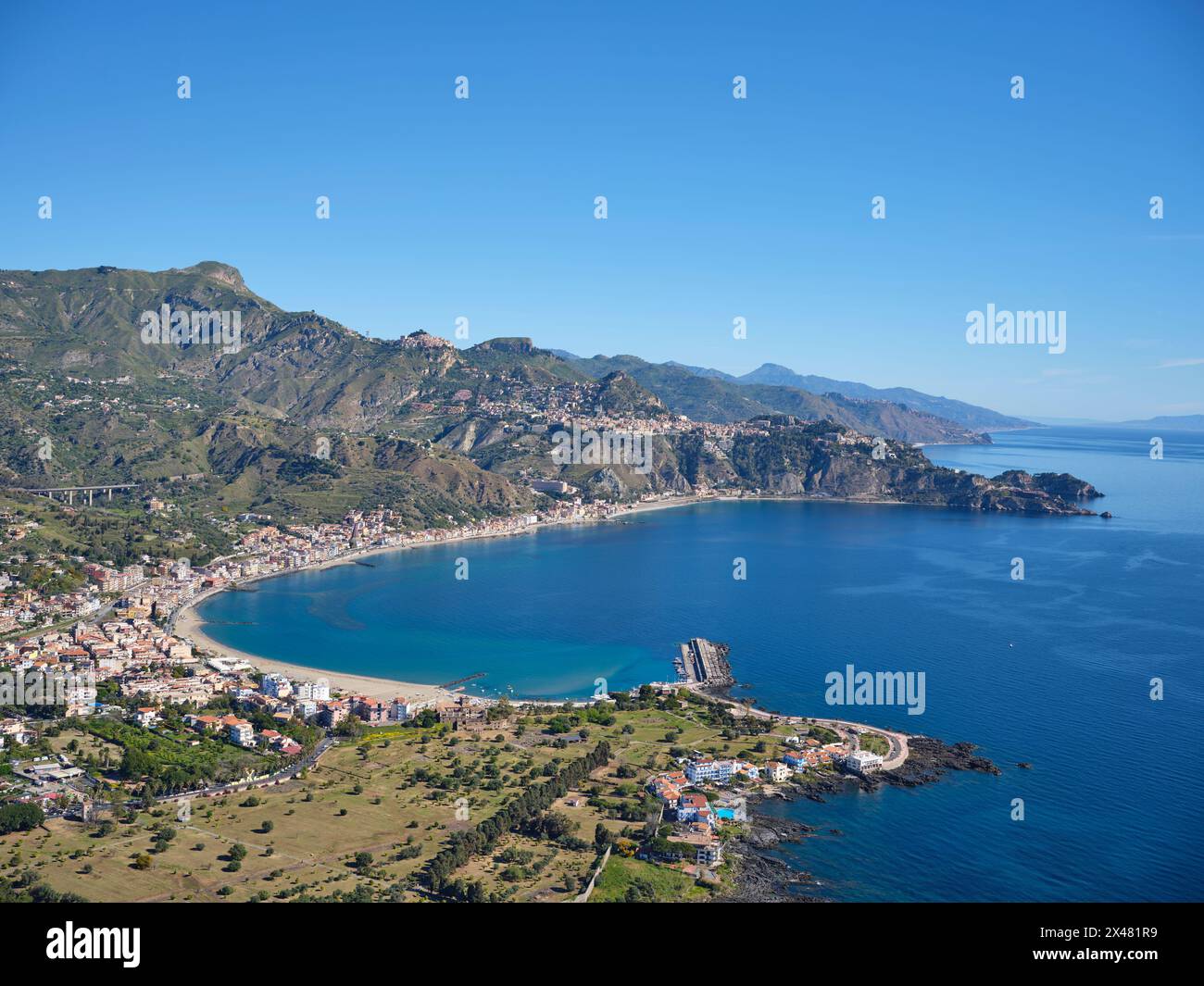 VISTA AEREA. I promontori rocciosi di Taormina che si estendono nel Mar Ionio. Città metropolitana di Messina, Sicilia, Italia. Foto Stock