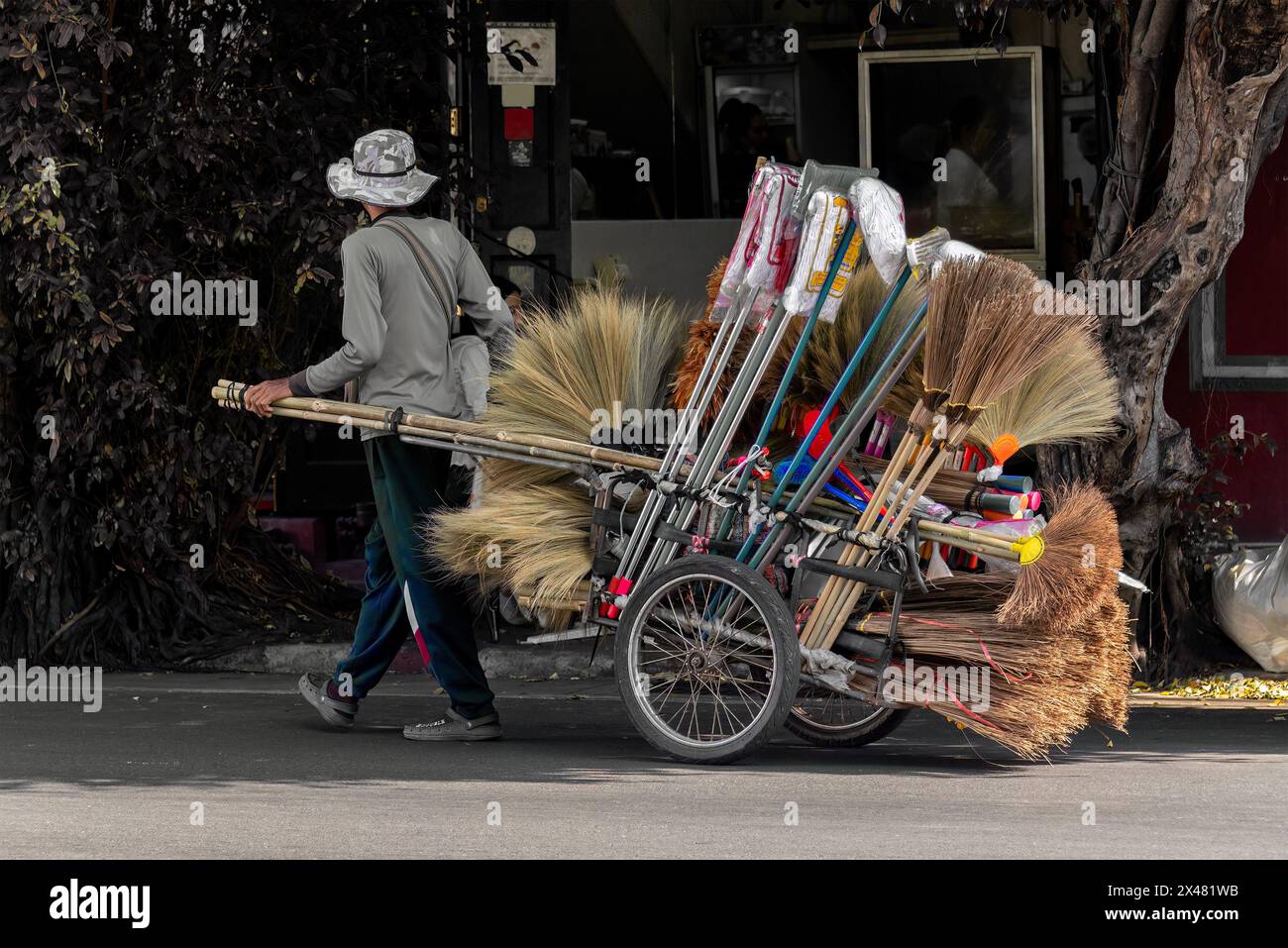 Bangkok, Thailandia, 18 gennaio 2023: La vita quotidiana di un commerciante con il suo carrello a due ruote che vende attrezzi per la pulizia. Foto Stock