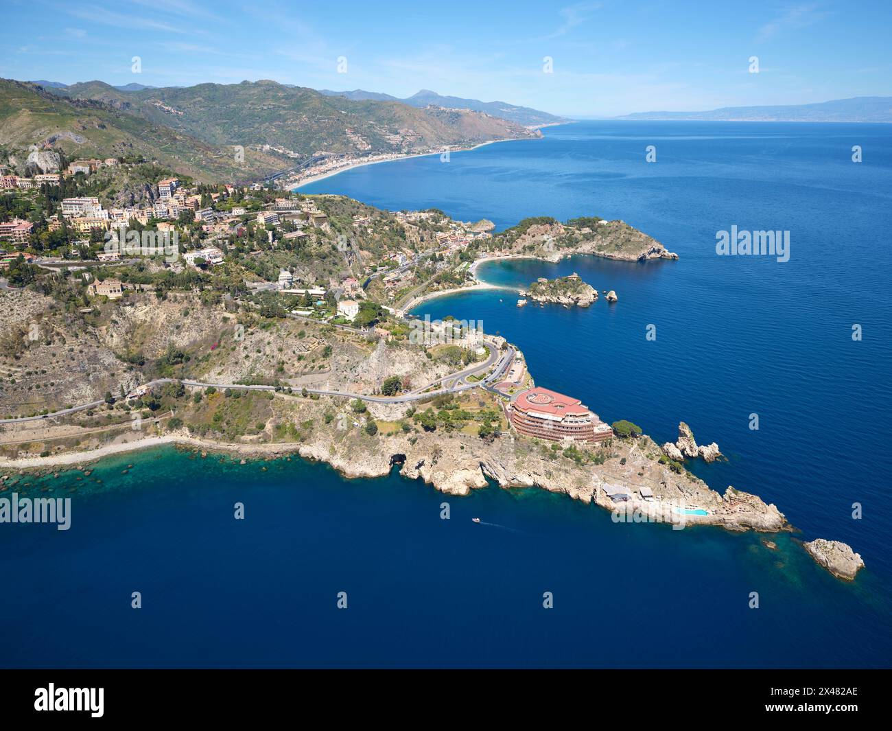 VISTA AEREA. I promontori rocciosi di Taormina che si estendono nel Mar Ionio. Città metropolitana di Messina, Sicilia, Italia. Foto Stock