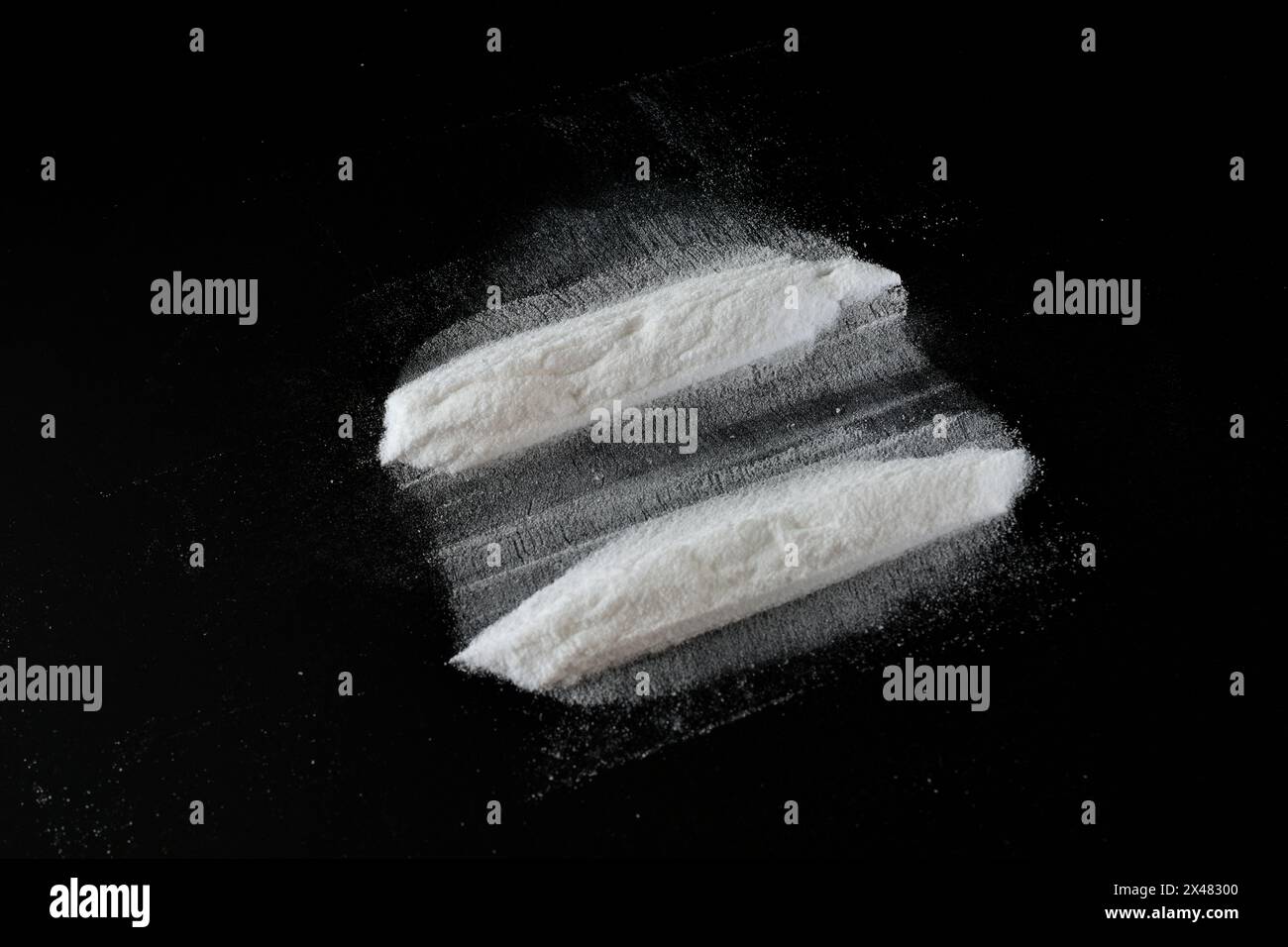 Una polvere bianca sconosciuta giace su uno sfondo nero in due lunghe strisce. Foto Stock