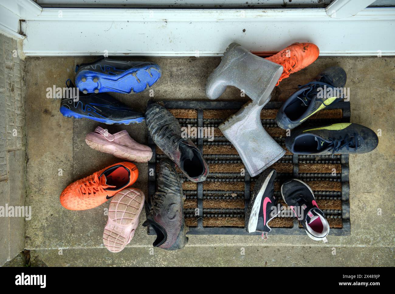 Assortimento di calzature per bambini poggiate sulla porta anteriore. Foto Stock