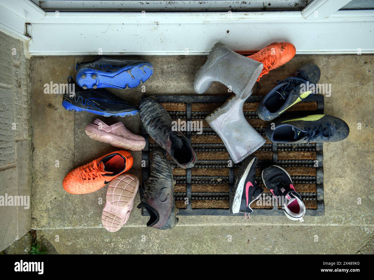 Assortimento di calzature per bambini poggiate sulla porta anteriore. Foto Stock