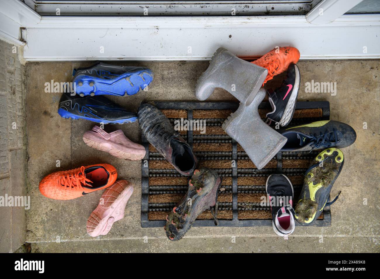 Assortimento di calzature per bambini poggiate sulla porta anteriore. Foto Stock