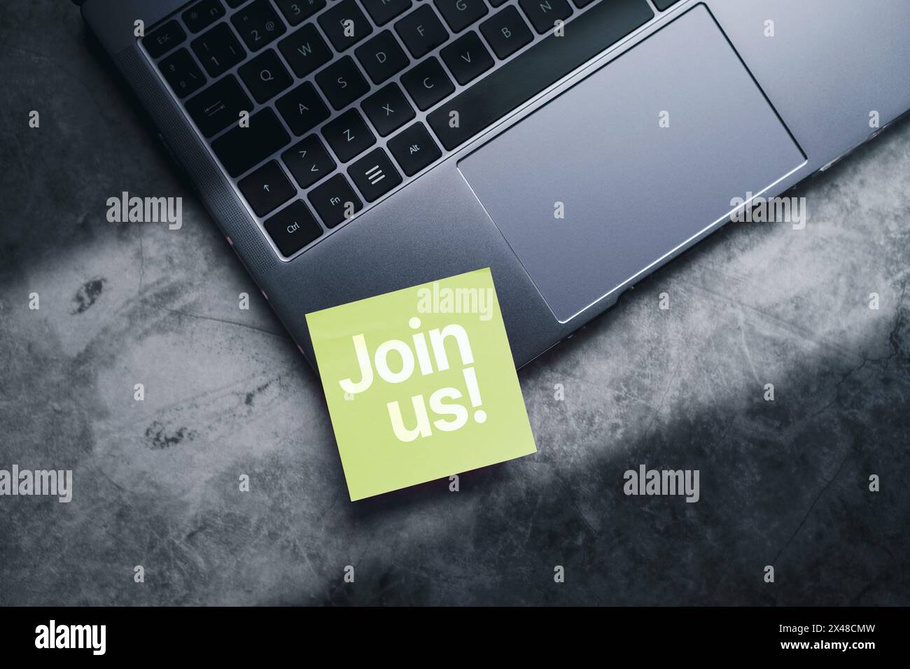 Nota adesiva verde con messaggio "join Us" sul laptop. Concetto aziendale di gestione e reclutamento. Opportunità di assunzione. Foto Stock