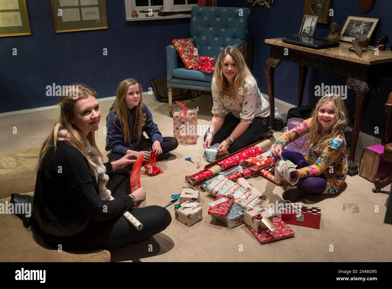 Madre e figlie confezionano regali nella casa di famiglia Dorset a Natale, Inghilterra, Regno Unito Foto Stock