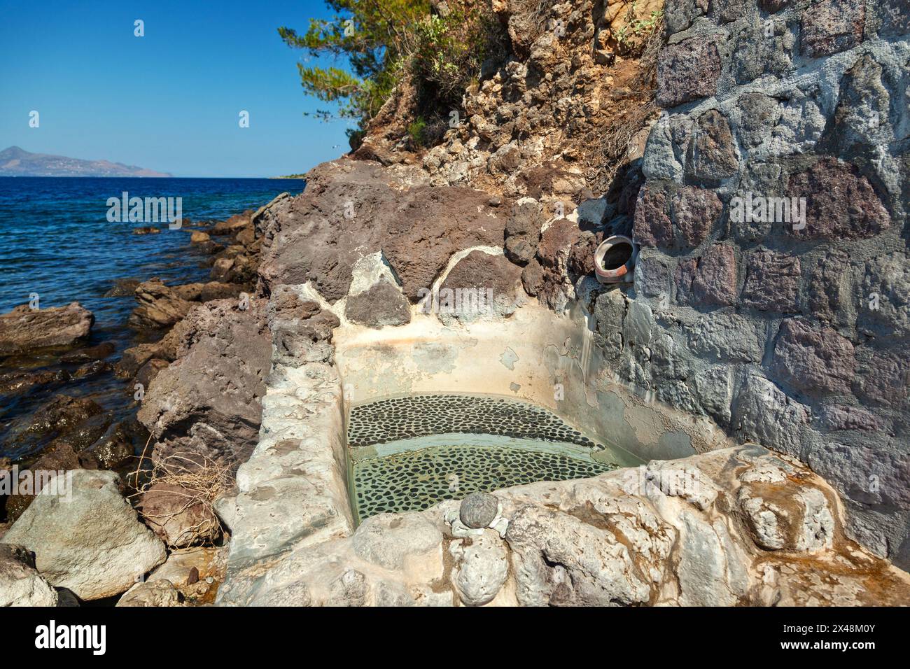 Le cosiddette Terme di Pausania a Methana, Grecia, presentano una piccola piscina che si riempie ogni 15 minuti per i visitatori che desiderano godersi le acque calde. Foto Stock