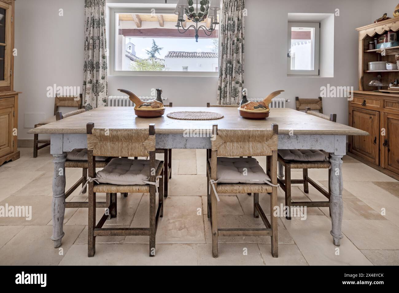Una sala da pranzo in una casa di campagna con pavimenti in marmo e splendidi mobili in legno in stile rustico Foto Stock