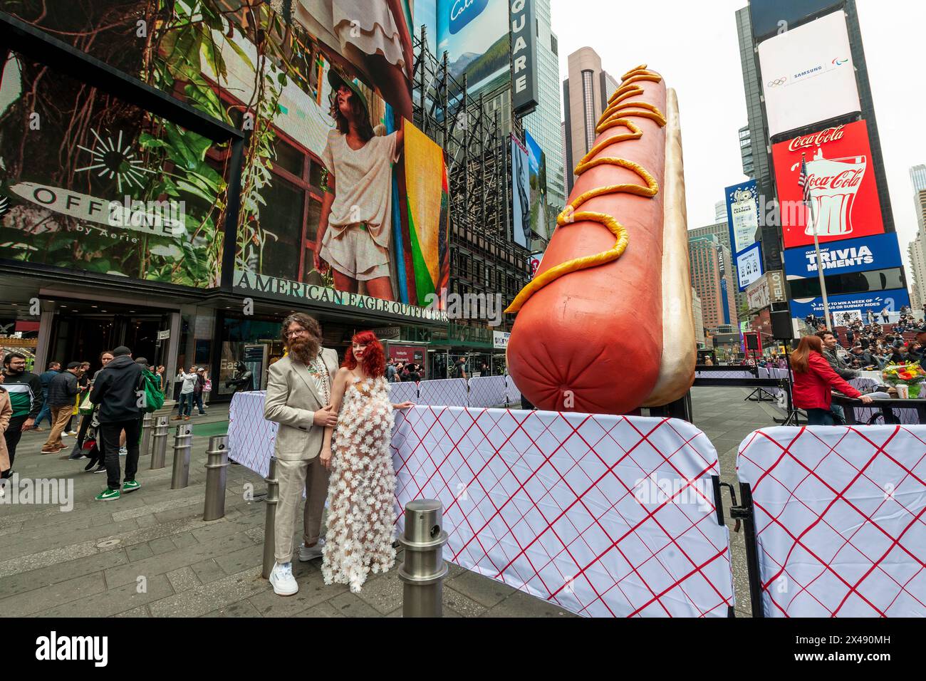 Gli artisti Jen Catron e Paul Outlaw posano di fronte a "Hot Dog in the City", a Times Square a New York martedì 30 aprile 2024. La scultura animatronica di hot dog lunga 65 metri si solleva e eiacula coriandoli a mezzogiorno ogni giorno. L'installazione sarà visibile fino al 13 giugno.(© Richard B. Levine) Foto Stock