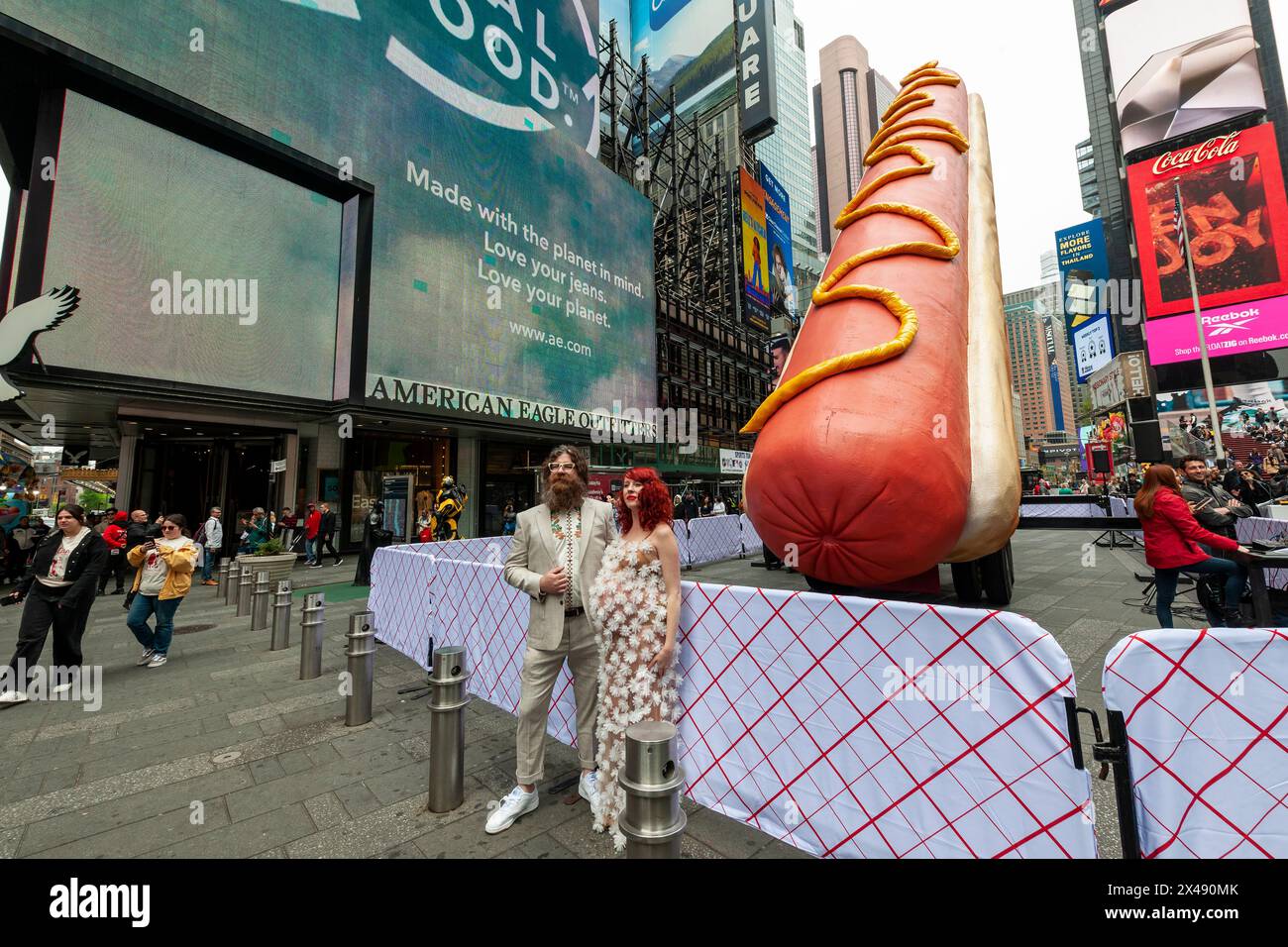 Gli artisti Jen Catron e Paul Outlaw posano di fronte a "Hot Dog in the City", a Times Square a New York martedì 30 aprile 2024. La scultura animatronica di hot dog lunga 65 metri si solleva e eiacula coriandoli a mezzogiorno ogni giorno. L'installazione sarà visibile fino al 13 giugno.(© Richard B. Levine) Foto Stock