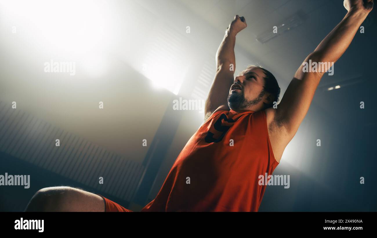 Giocatore di pallacanestro su sedia a rotelle che celebra il gol perfetto con le mani alzate dopo un tiro di successo. Abilità di una persona vincente con disabilità. Coinvolgente ritratto angolare olandese Foto Stock