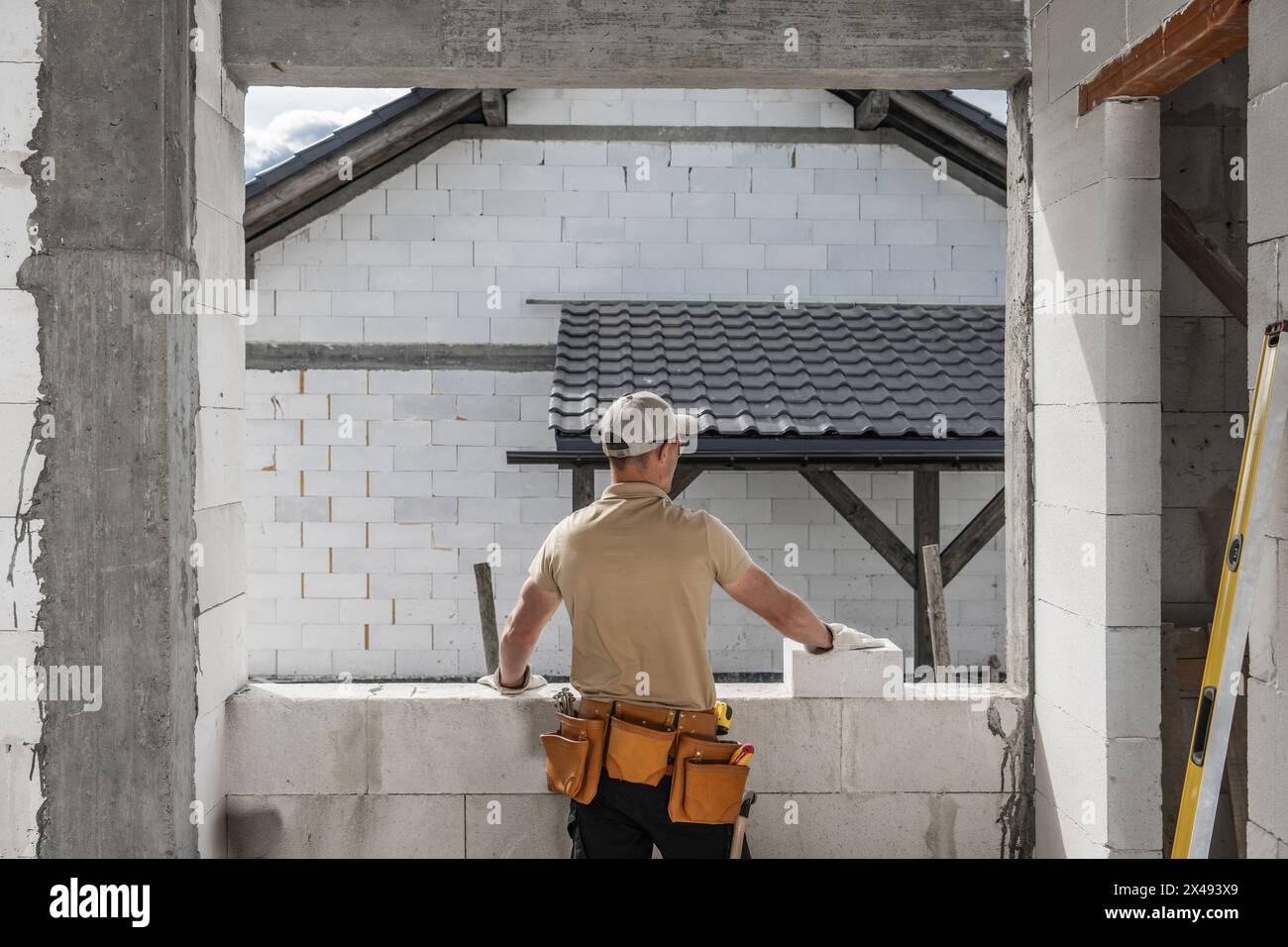Il lavoratore edile di concrete Bricks House guarda fuori da una finestra futura Foto Stock