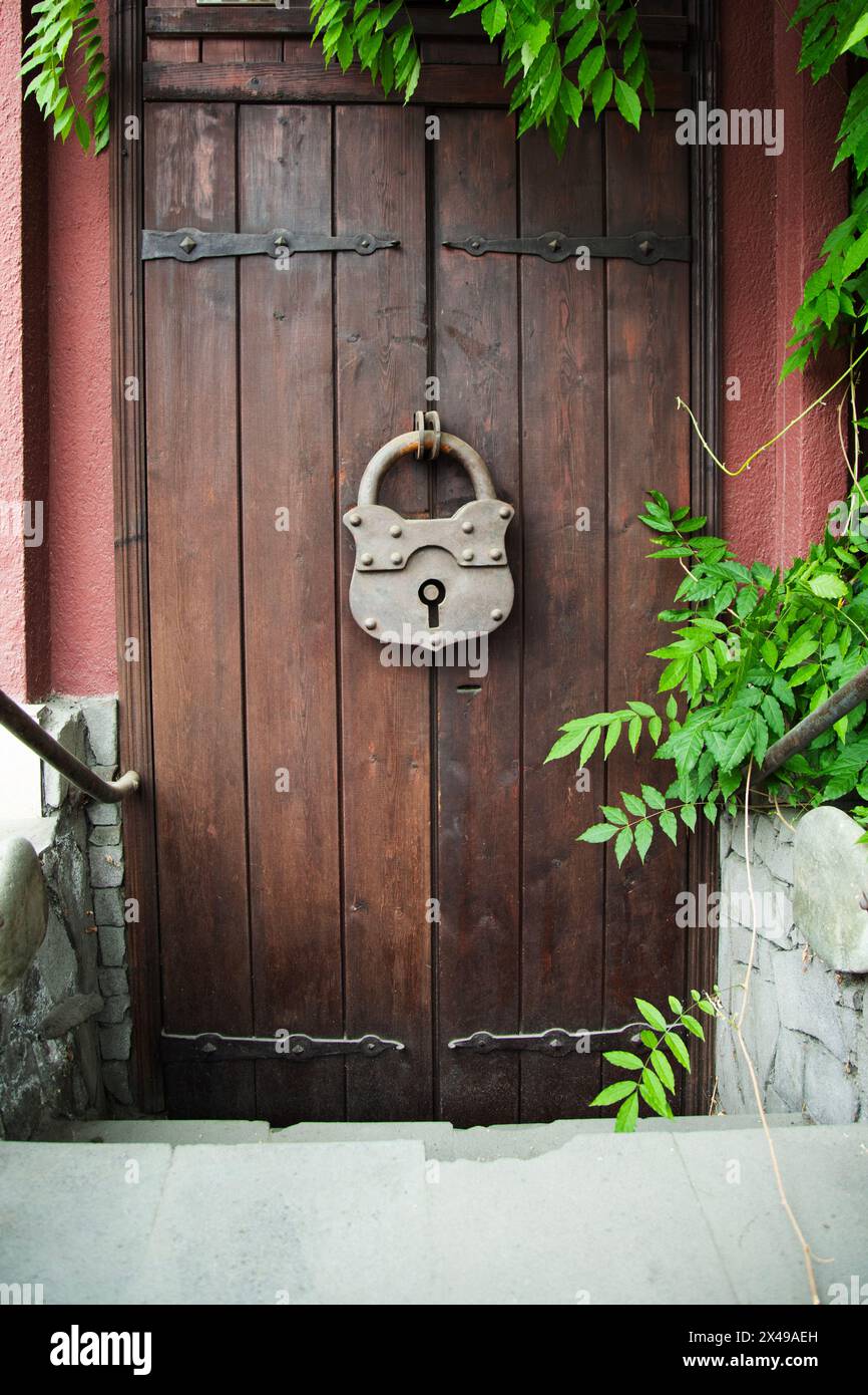 Porta in legno con grande serratura in ferro incernierata nel Villaggio. Stile rustico Foto Stock