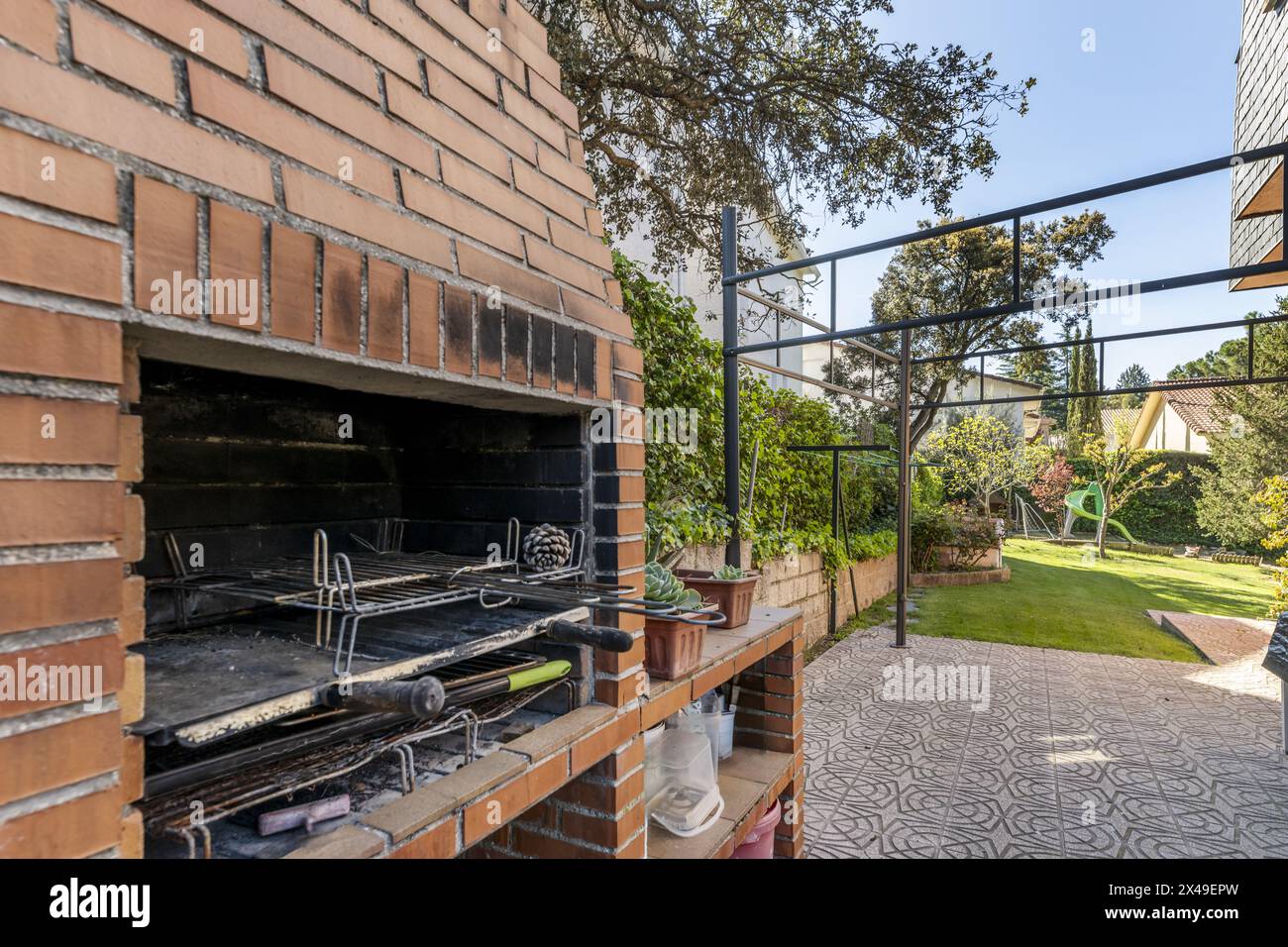barbecue incorporato con vigne da giardino con un sentiero piastrellato e un giardino con erba sullo sfondo Foto Stock