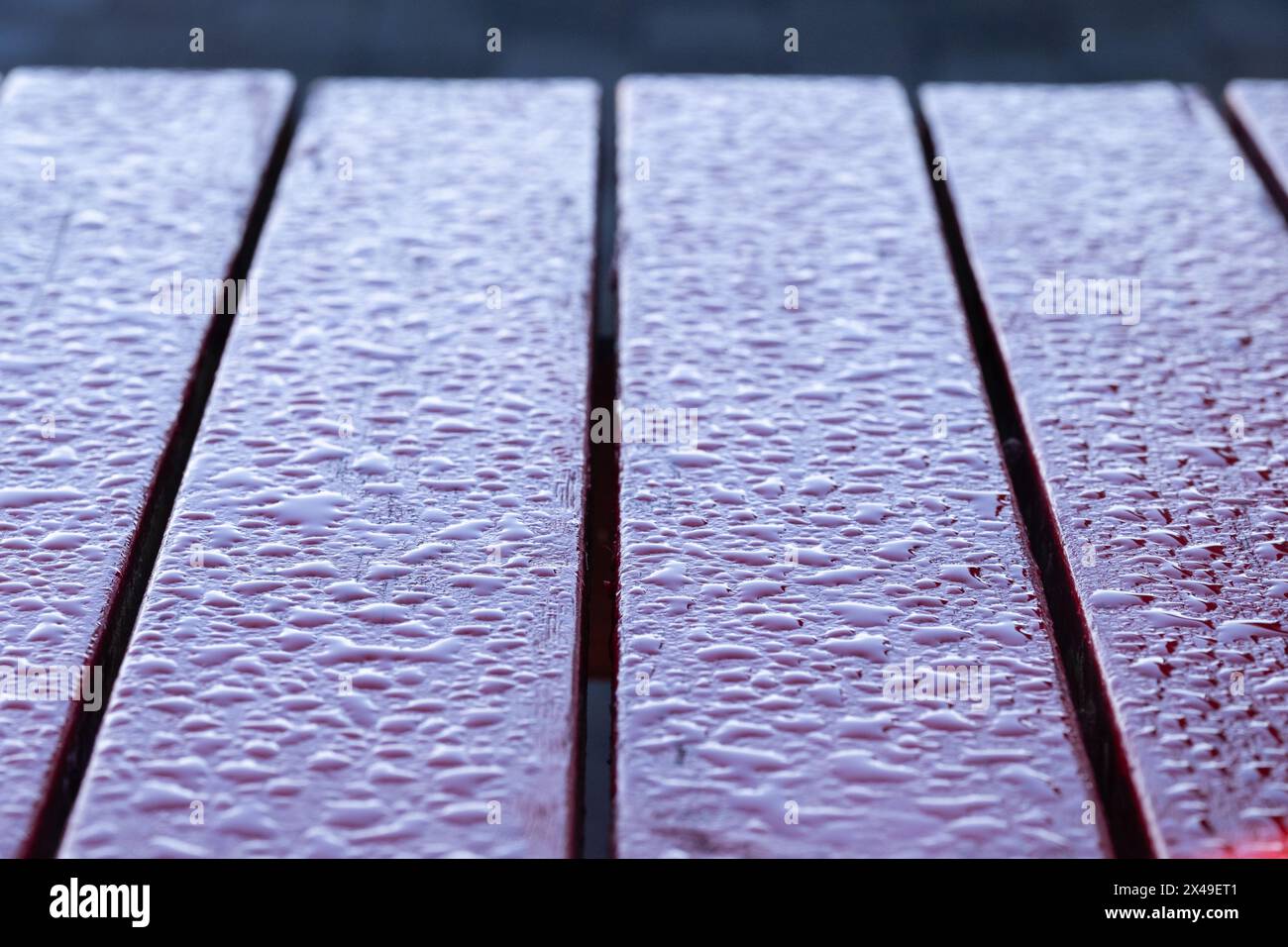 Un tavolo in legno con superficie bagnata. Le goccioline d'acqua sul tavolo creano un senso di calma e tranquillità. Il tavolo sembra essere all'aperto, possi Foto Stock