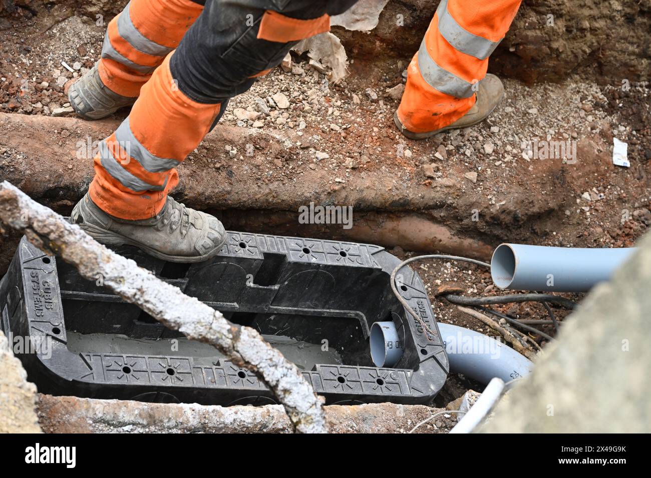 Operai Openreach che installano scatole di derivazione sotterranee e anatre di cavi sul ciglio della strada per il cavo in fibra ottica per la banda larga e il telefono, Regno Unito Foto Stock