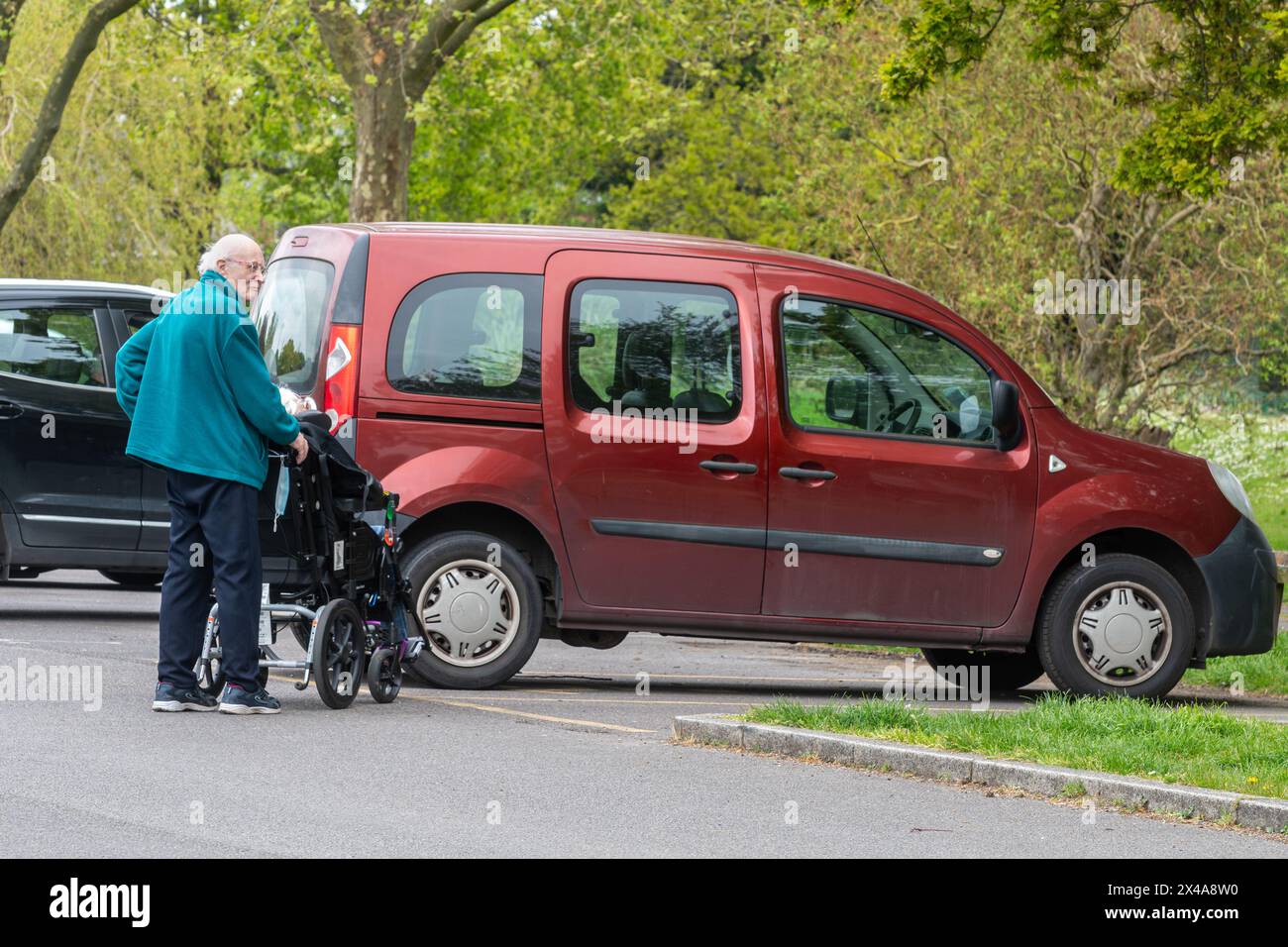 Uomo anziano che si prende cura della moglie disabile su una sedia a rotelle, Inghilterra, Regno Unito. Concetto: Assistenti non retribuiti, assistenza inadeguata per anziani e disabili Foto Stock