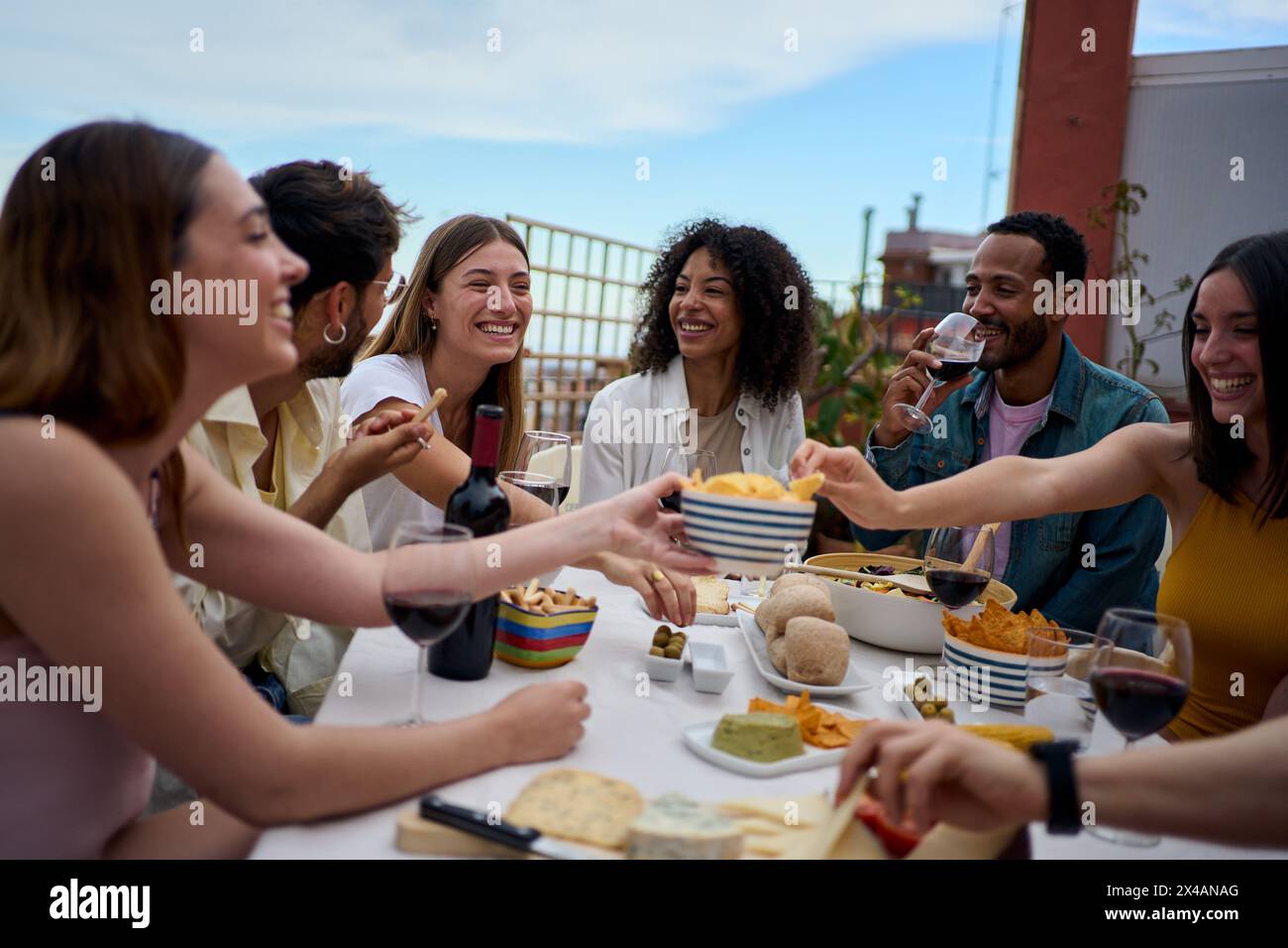 Gruppo di giovani amici multietnici che gusteranno il pasto riuniti sul tetto Foto Stock
