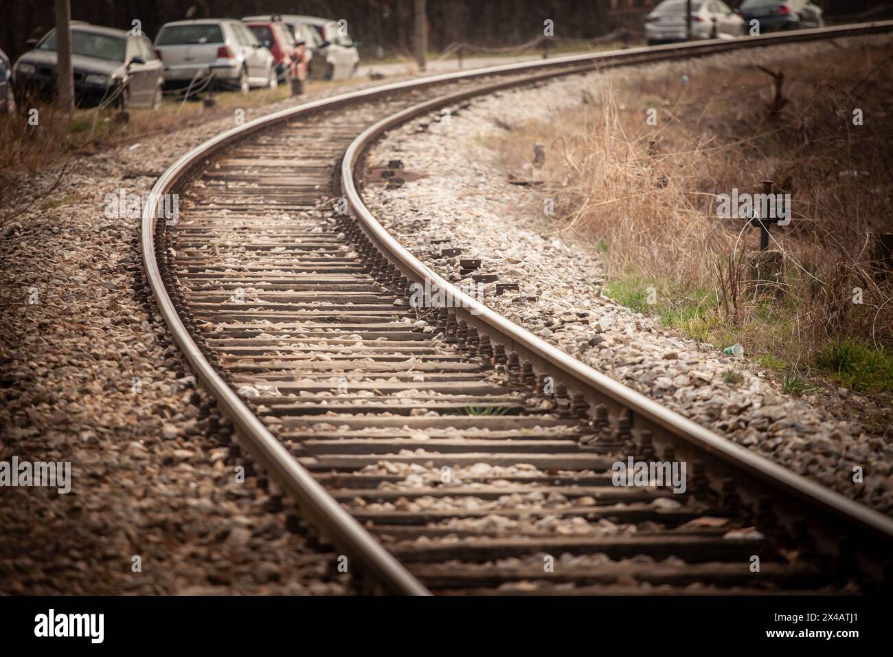 La fotografia cattura l'essenza del viaggio ferroviario e delle infrastrutture, con un binario curvo fiancheggiato da traverse in legno e ghiaia. Questo trasf Foto Stock