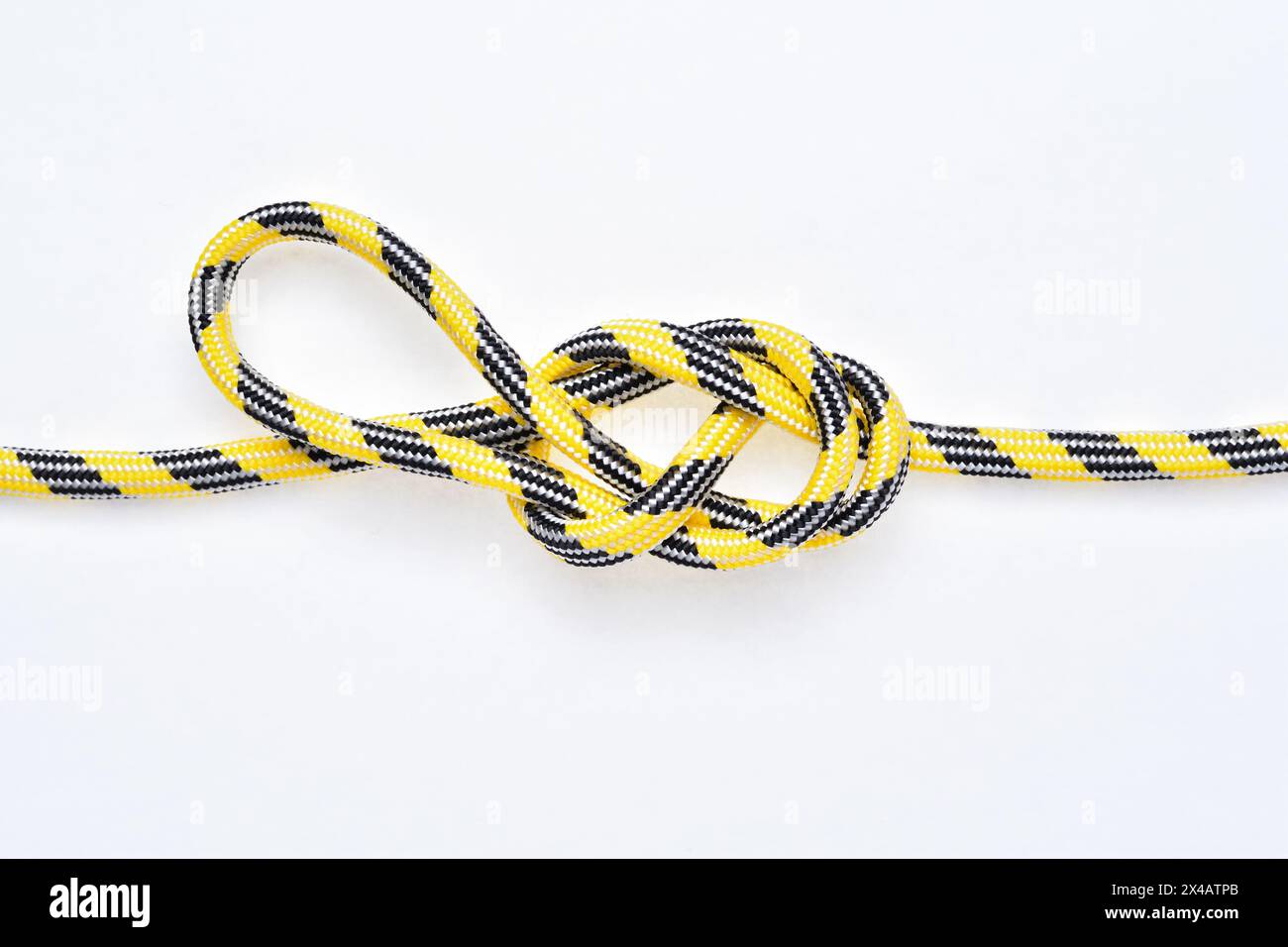 Figura 8 nodo ad anello direzionale su corda in nylon gialla e nera su sfondo bianco. Foto Stock