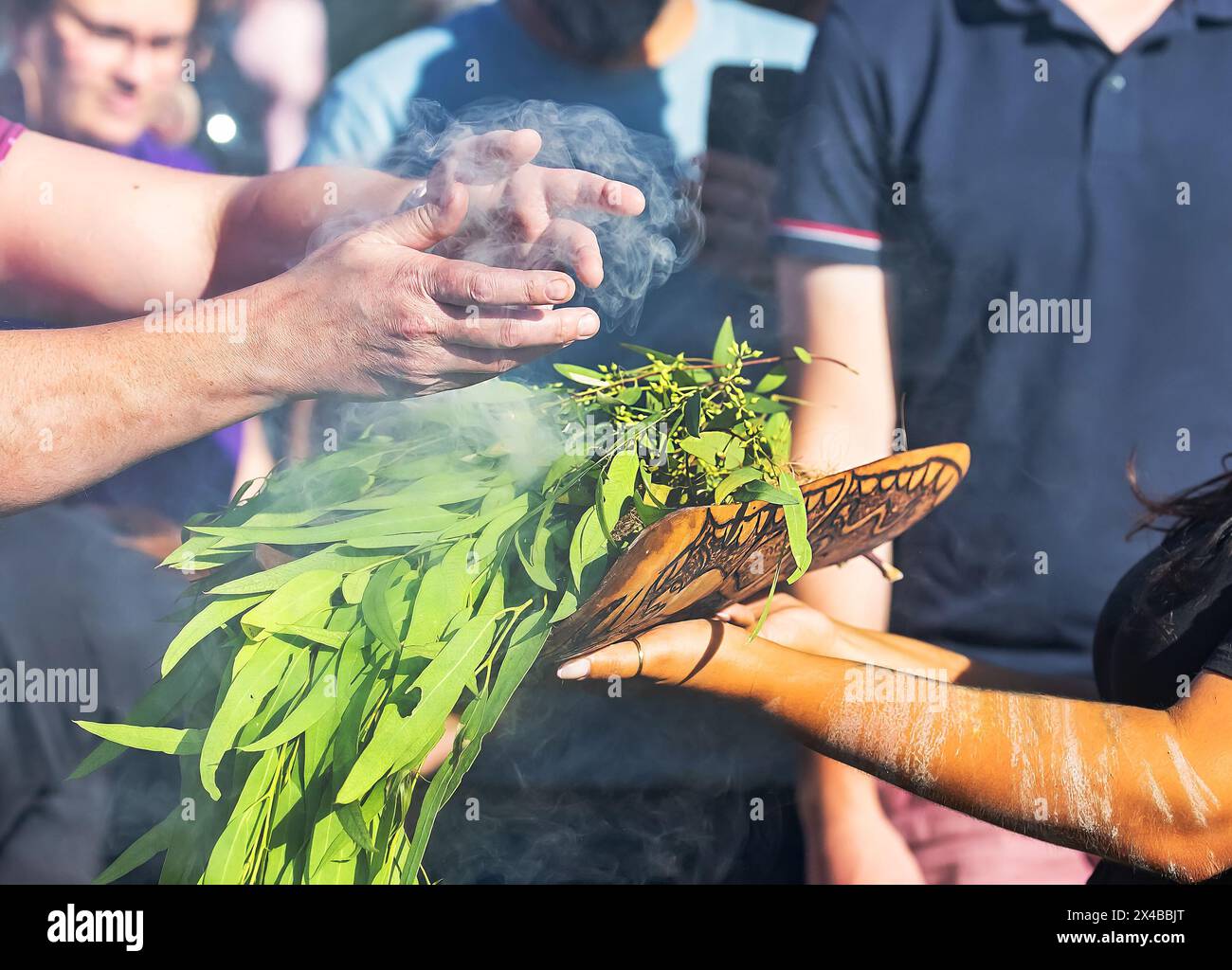 Fuoco rituale con ramo in fiamme verdi, fumo e fuoco, il rito rituale del fumo in un evento della comunità indigena in Australia Foto Stock