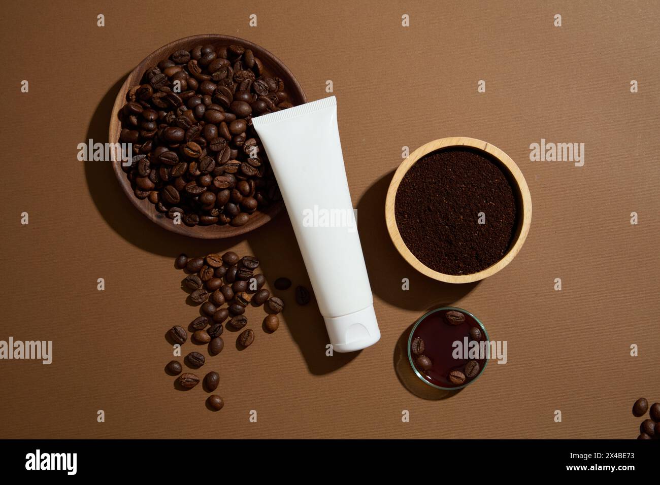 Scena minimalista per la pubblicità di cosmetici con ingredienti naturali. Vista dall'alto di una bottiglia di plastica bianca senza etichetta decorata con una ciotola di caffè in legno Foto Stock