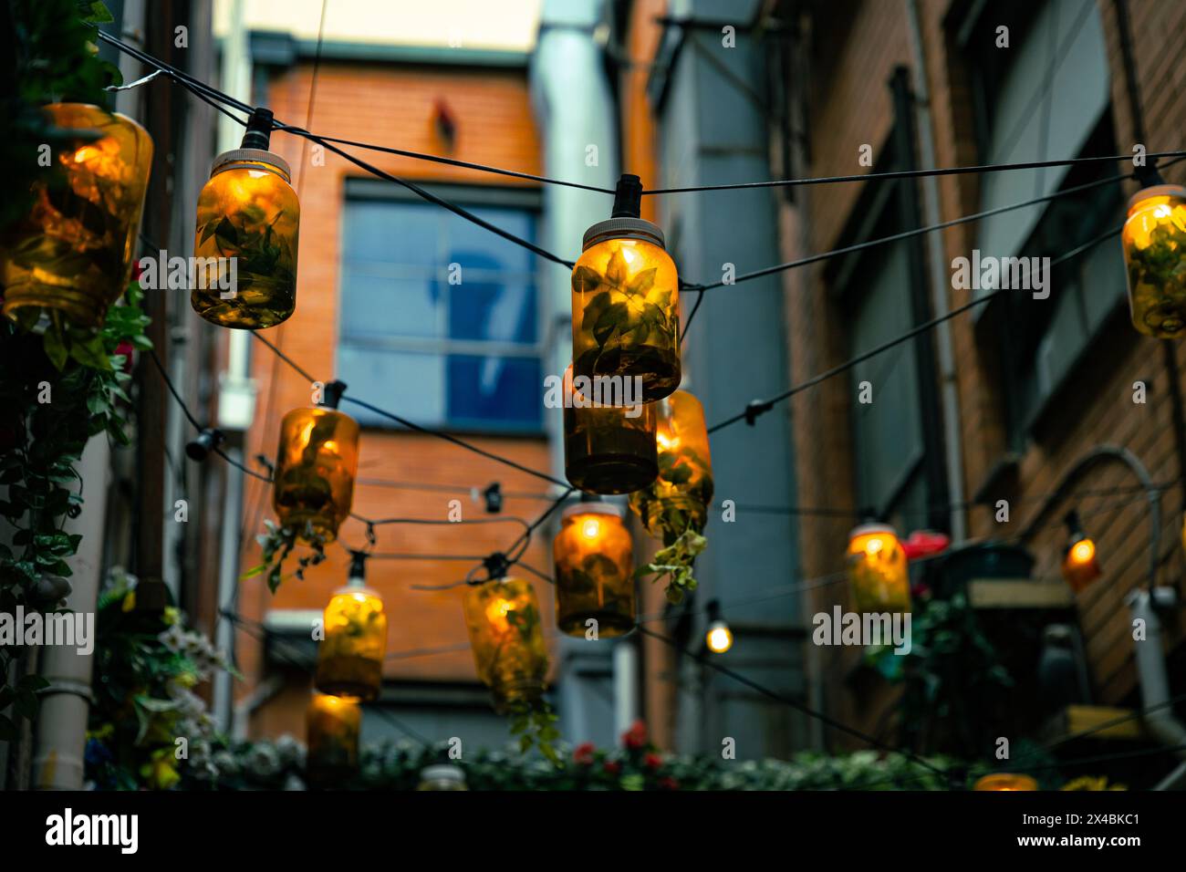 I vasetti mason riutilizzati illuminano un vicolo urbano. Foto Stock