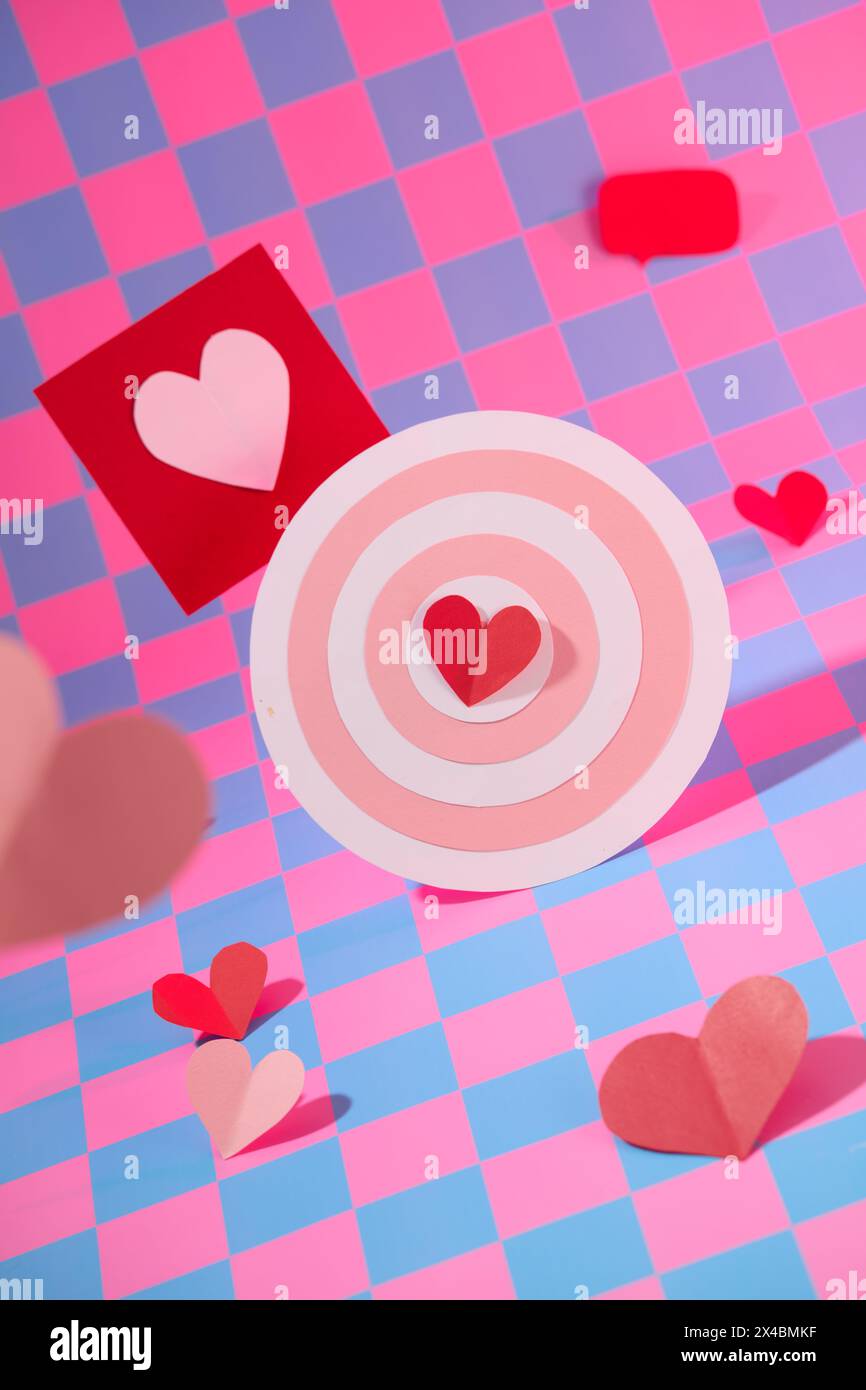 Vista frontale di un carino busto decorato con cuori di carta rossa e carte decorate su sfondo a scacchi rosa e viola. Scena minima per la pubblicità Foto Stock