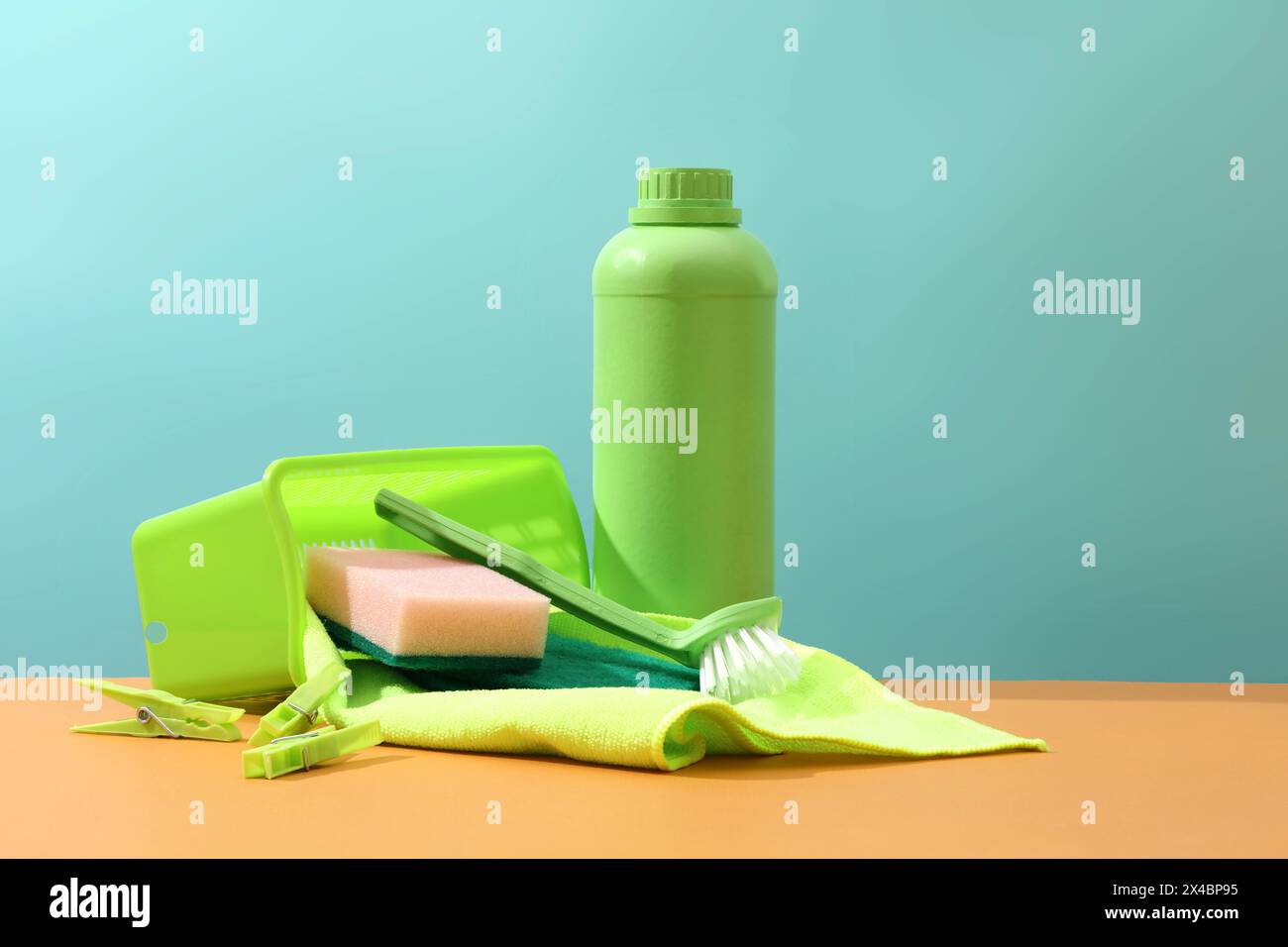 Vista frontale del flacone verde con tergicristallo, spazzola, spugna e clothespins visualizzati su sfondo blu. Scena minima per la pubblicità, mockup per Foto Stock
