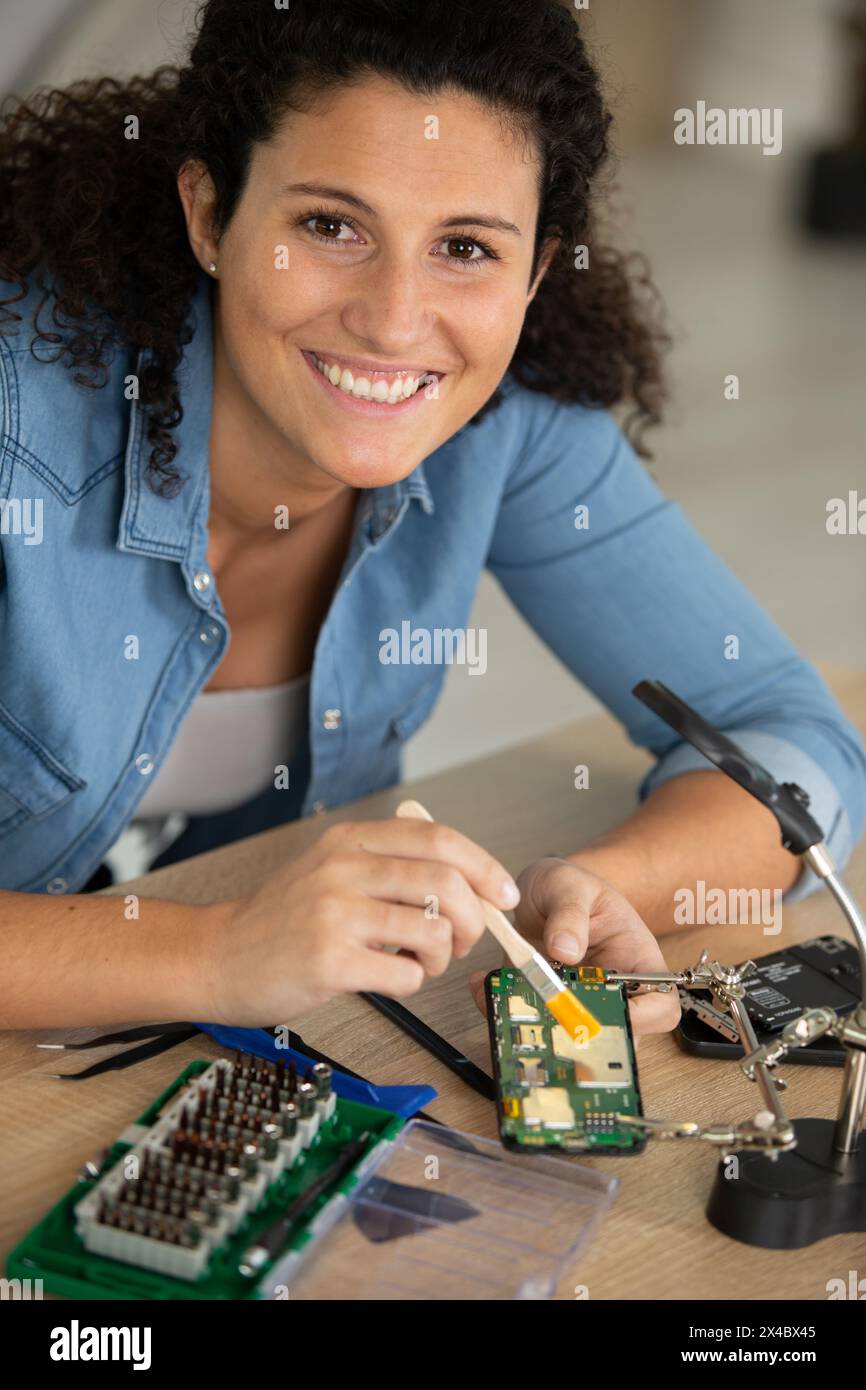 una donna felice che ripara il computer Foto Stock