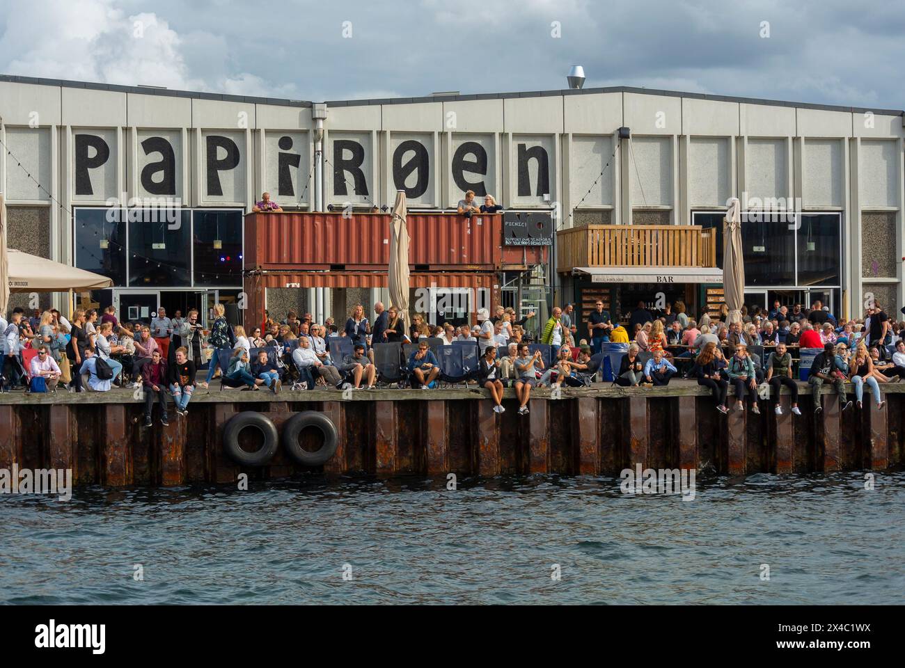 Copenhagen, Danimarca, grande folla di persone, condivisione di bevande al bar locale "Papiroen" sul fiume, alla moda Foto Stock
