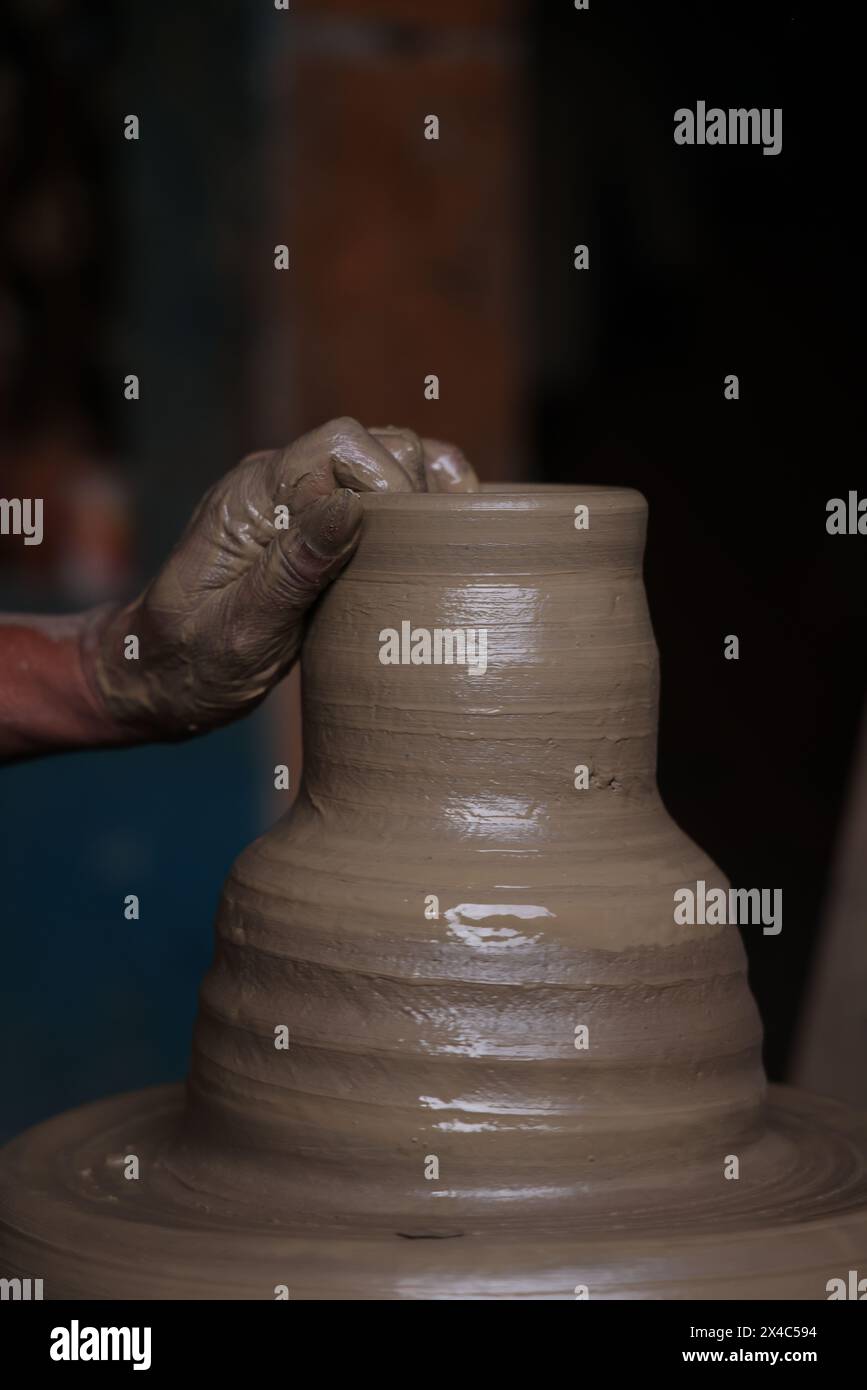 Il vasaio lavora su una ruota di ceramica fatta di argilla dai colori tenui, pentole di argilla dai colori retrò con mano e attrezzature Foto Stock