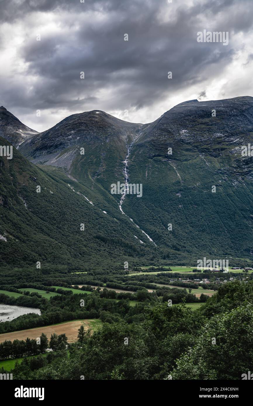 Torreggiante monte Litlkalkinn, un ruscello che scorre lungo la montagna verso la valle in un buio drammatico e nuvoloso giorno d'estate, Sunndalsøra in Norvegia Foto Stock