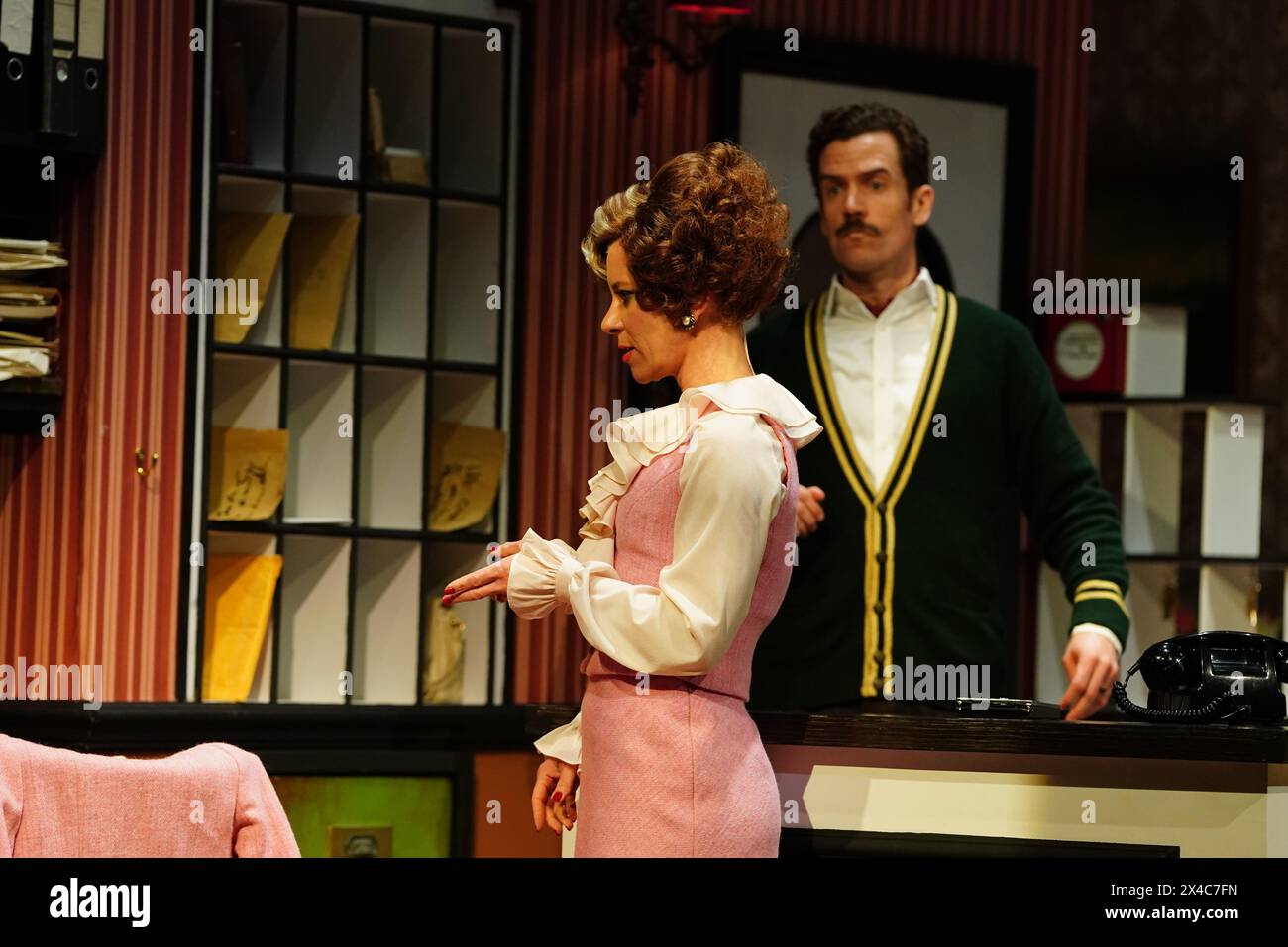 Adam Jackson-Smith interpreta Basil Fawlty e Anna-Jane Casye interpreta Sybil eseguendo una scena durante una chiamata fotografica per i media prima dell'apertura di Fawlty Towers The Play, che apre sabato all'Apollo Theatre, nel centro di Londra. Data foto: Giovedì 2 maggio 2024. Foto Stock