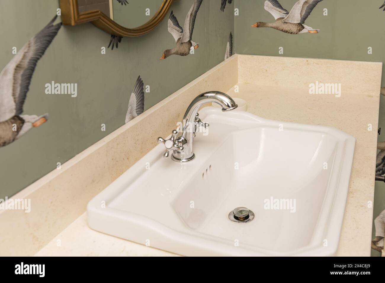 Lavabo in porcellana vintage con rubinetto cromato e ripiano in marmo crema Foto Stock