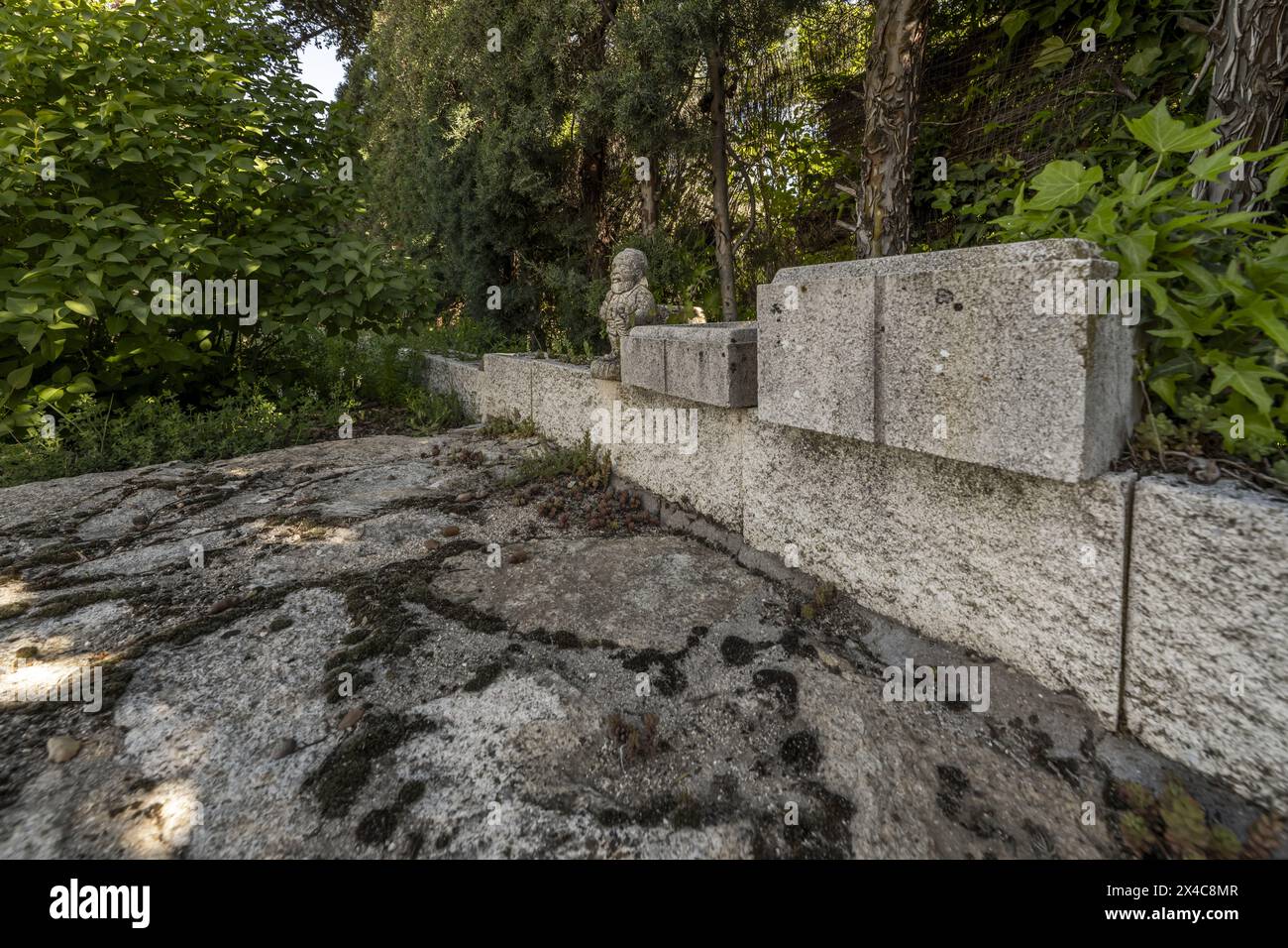 Recinzione perimetrale di un giardino con siepi e oggetti decorativi in pietra Foto Stock