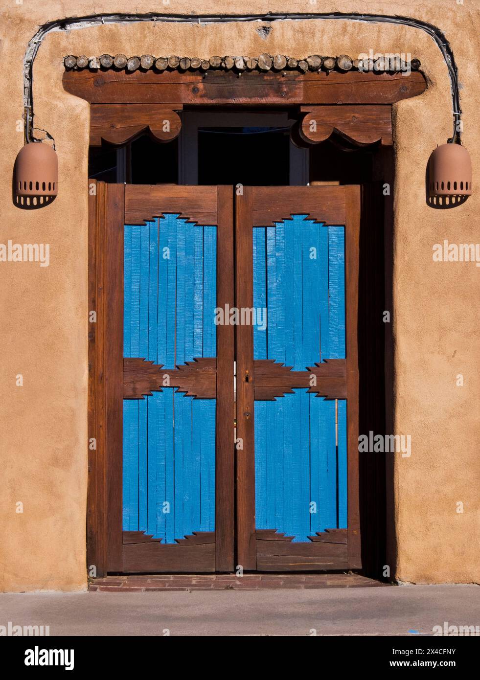 Stati Uniti, nuovo Messico, Sante Fe. Porta colorata in turchese e legno con lampade d'accento su una casa in adobe. Foto Stock