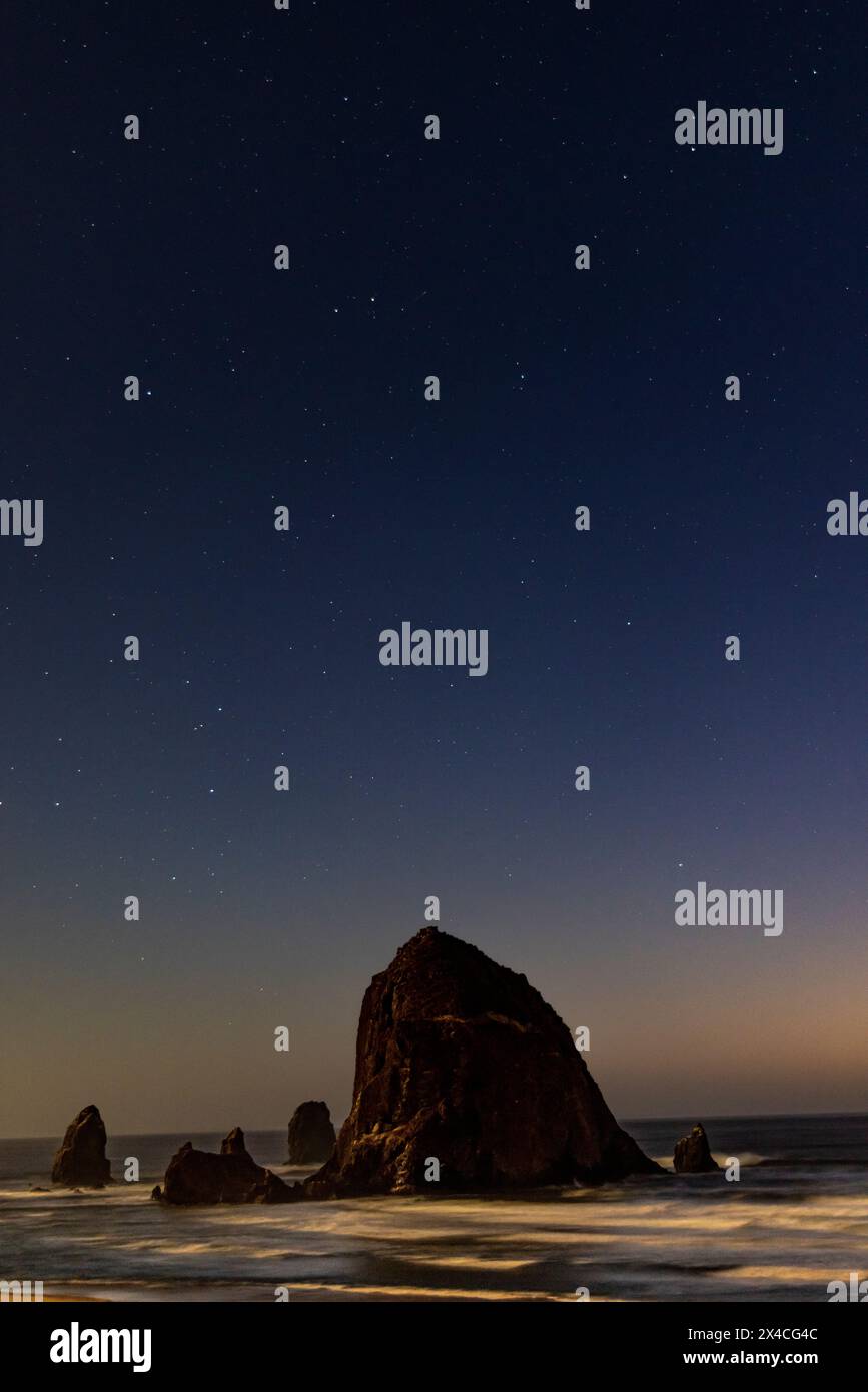Stati Uniti, Oregon. Cannon Beach e Haystack Rock luci e stelle serali. Foto Stock