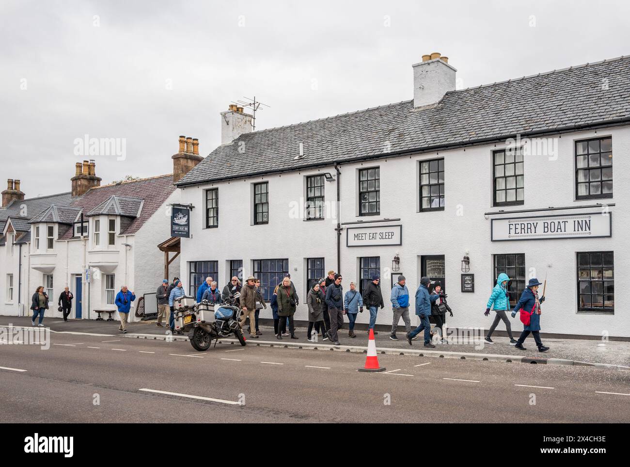 I turisti al largo della nave da crociera vichinga Saturno vichingo camminano con la loro guida nella città di pescatori di Ullapool nelle Highlands scozzesi. Foto Stock