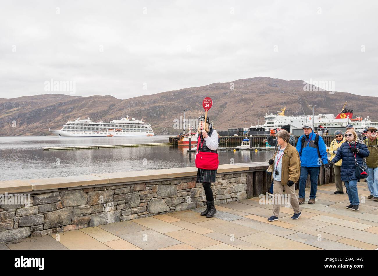 I turisti al largo della nave da crociera vichinga Saturno vichingo camminano con la loro guida nella città di pescatori di Ullapool nelle Highlands scozzesi. Foto Stock