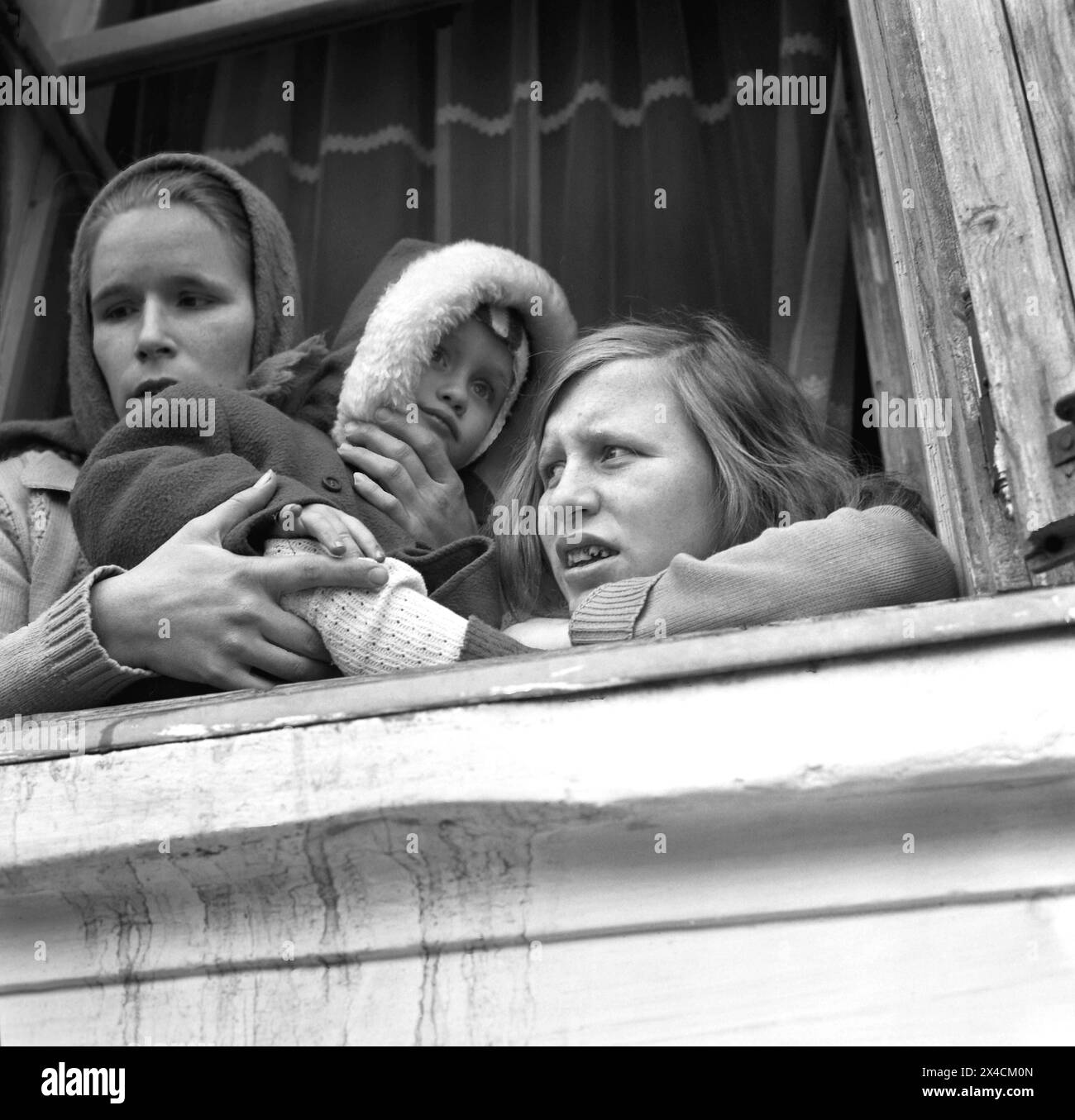 Repubblica Socialista di Romania negli anni '1970 Ragazze in una città provinciale sedute su un davanzale, che tengono un bambino. Foto Stock