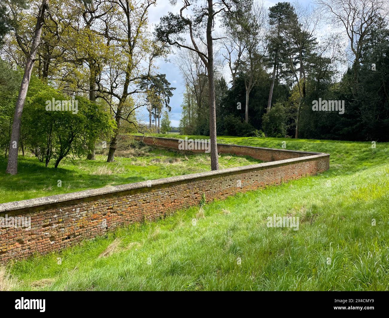 Un muro di mattoni su una tenuta di campagna raffigura il perimetro che racchiude un bosco. Foto Stock