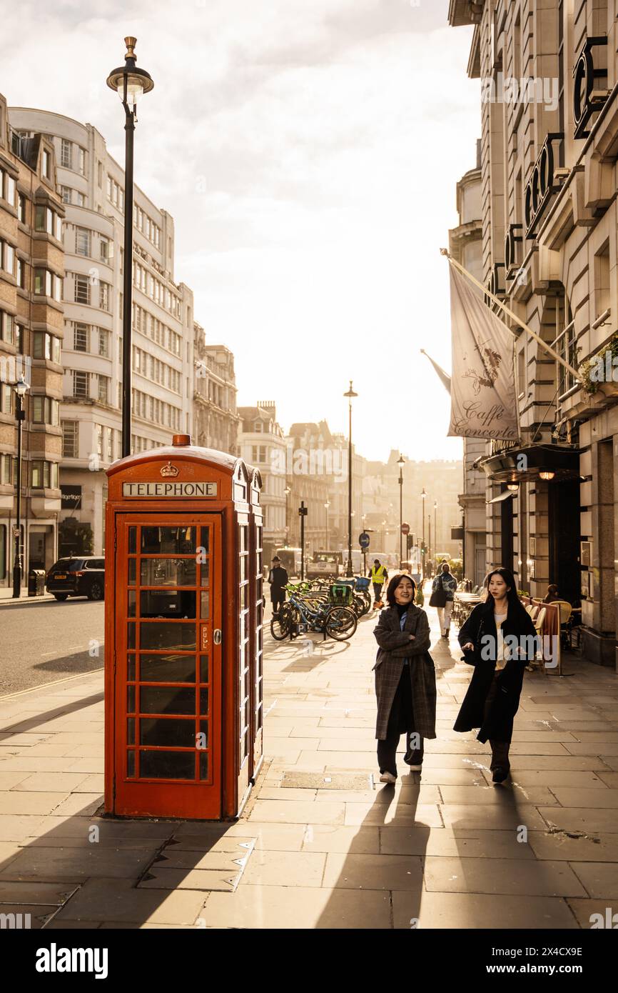 Momenti felici – due ragazze che ridono accanto all'iconica cabina telefonica rossa di Londra Foto Stock