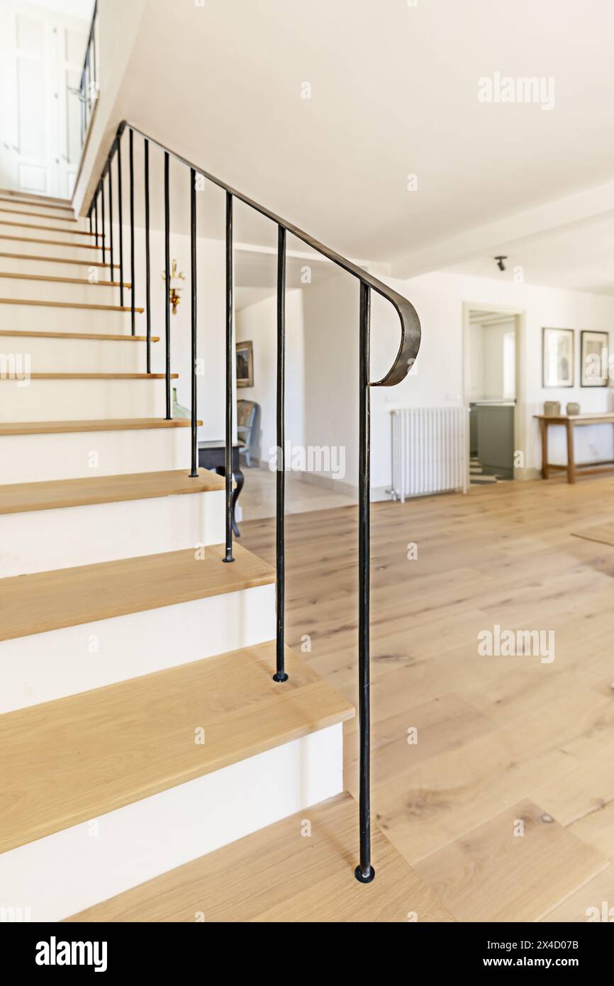 Scala in legno di una casa unifamiliare con ringhiera in metallo in stile minimalista Foto Stock