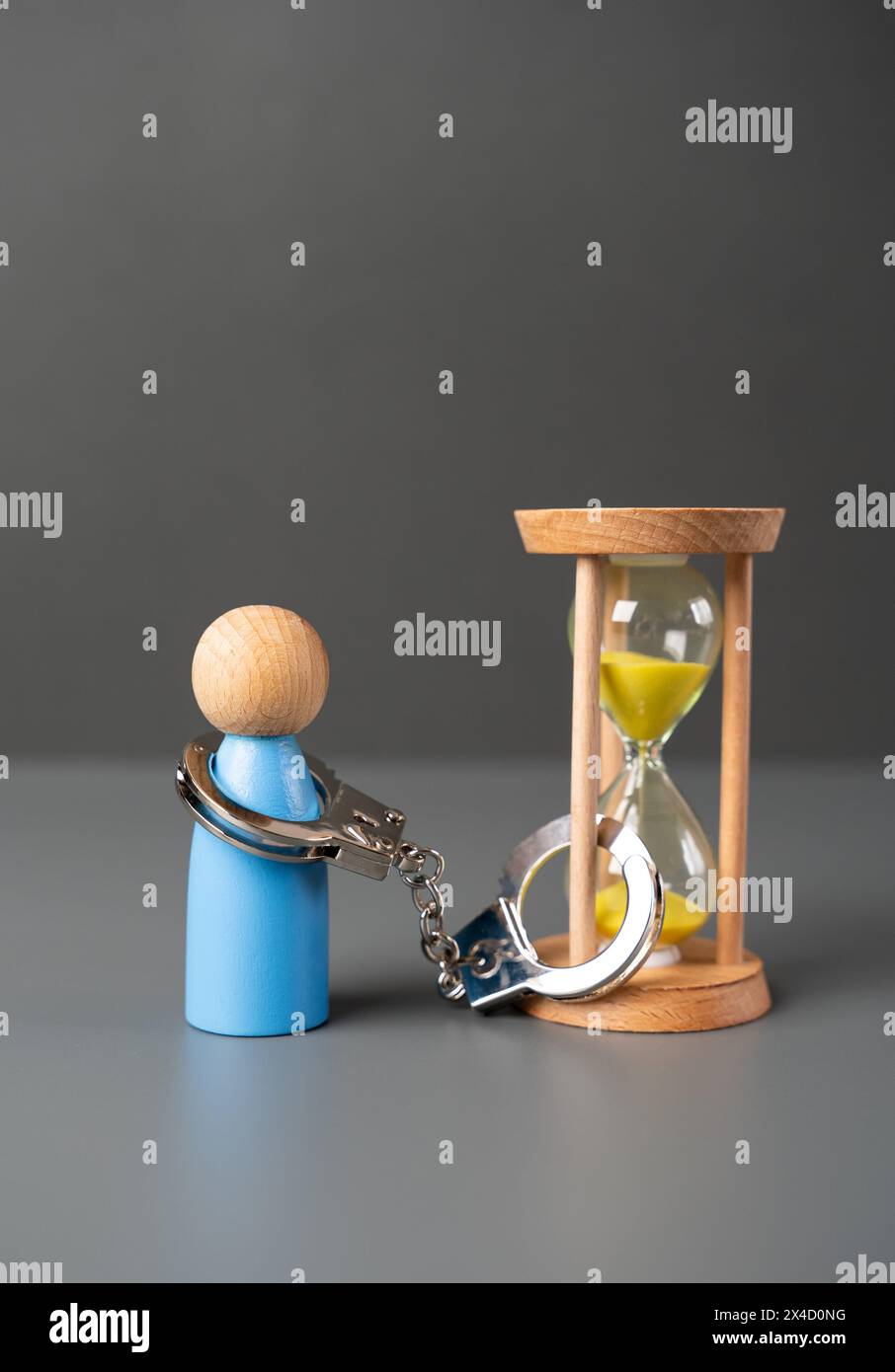 Un uomo è ammanettato ad una clessidra. Tempo limitato. Condizioni di un contratto. La reclusione e la reclusione per un certo periodo. Tempo rimanente nella vita. Foto Stock