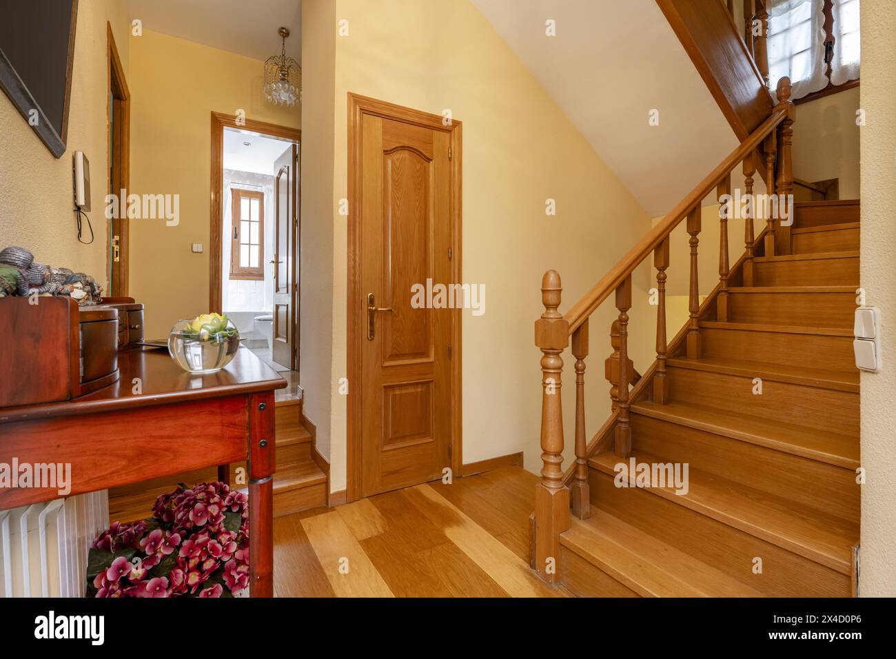 Scala interna di una casa unifamiliare con pianerottolo con una credenza in legno con balaustre in legno di quercia e pavimento dello stesso materiale Foto Stock