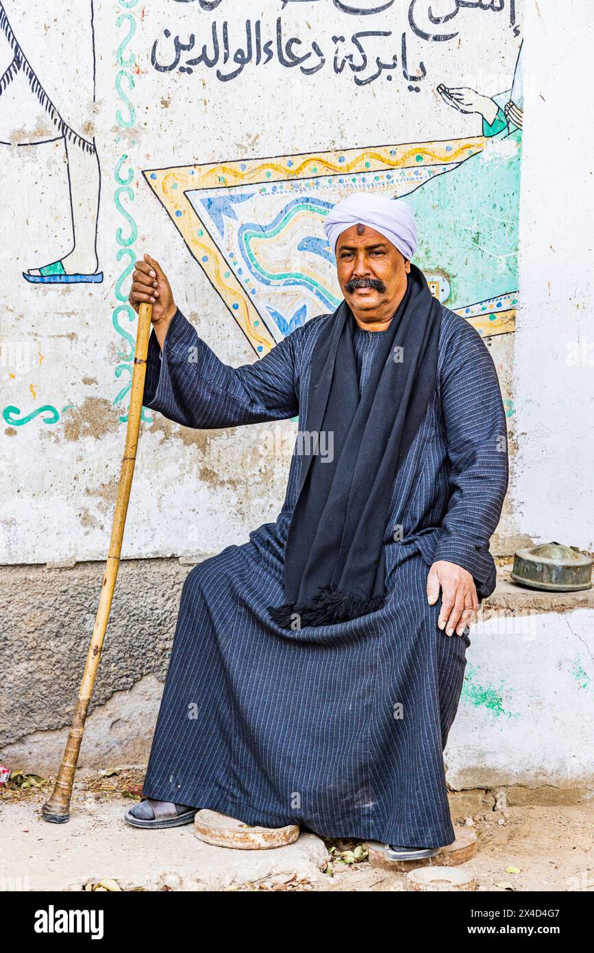 Tebe, Luxor, Egitto. Uomo seduto di fronte a murales contemporanei. (Solo per uso editoriale) Foto Stock